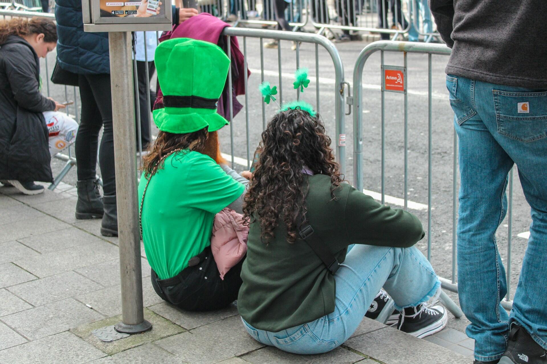 People wearing green, sitting on pavement.
