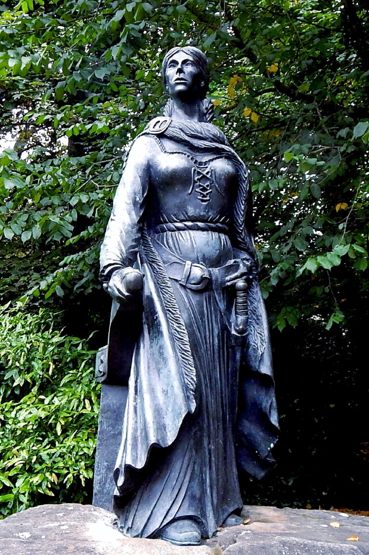A statue of a woman in a park.