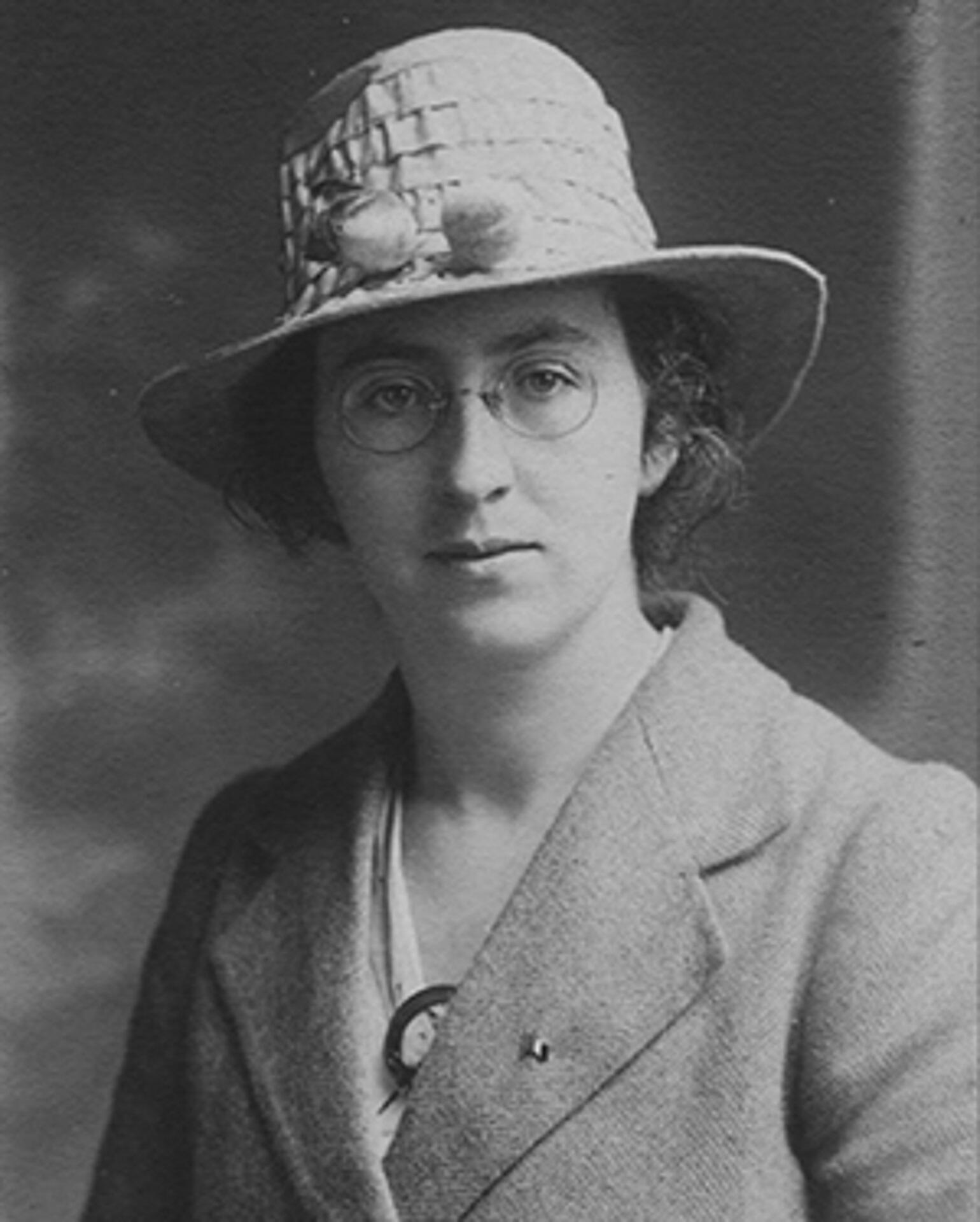 A woman wearing a hat, glasses and a coat.