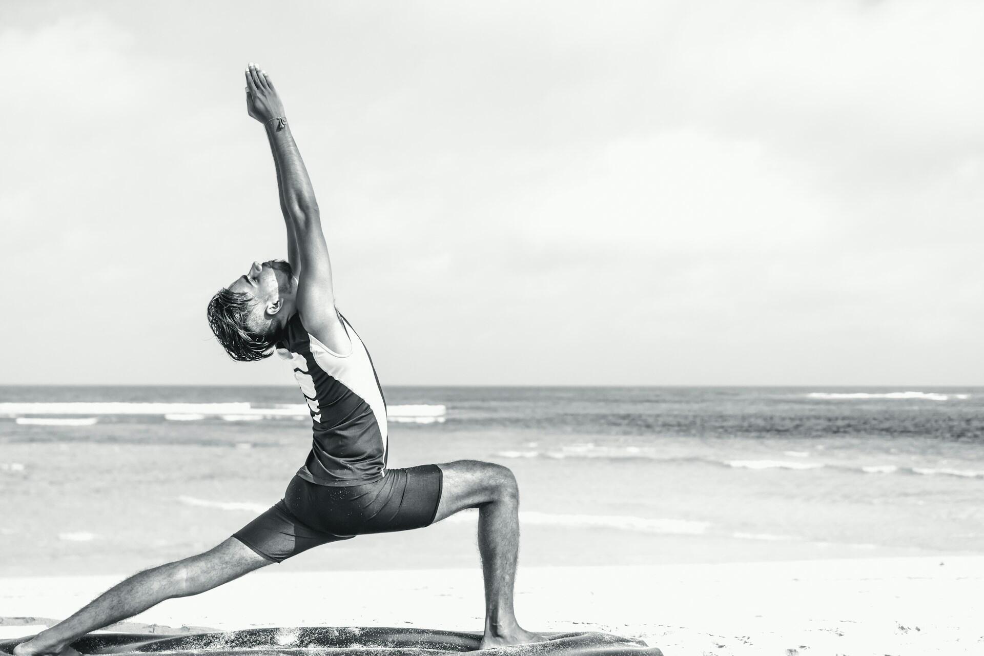 Person doing a yoga pose on the beach in black and white.