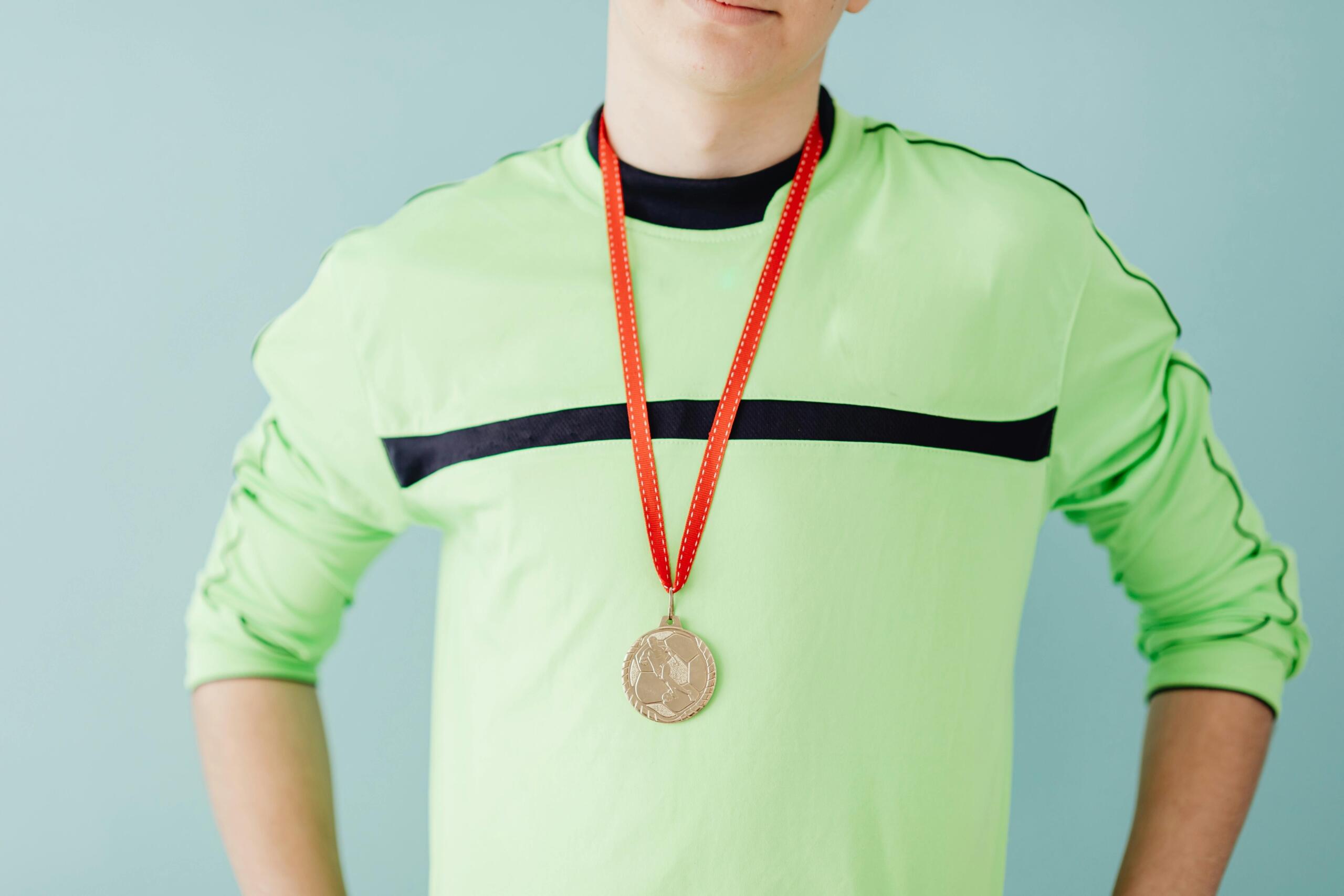A young boy in a sweatshirt proudly wearing a medal around his neck.