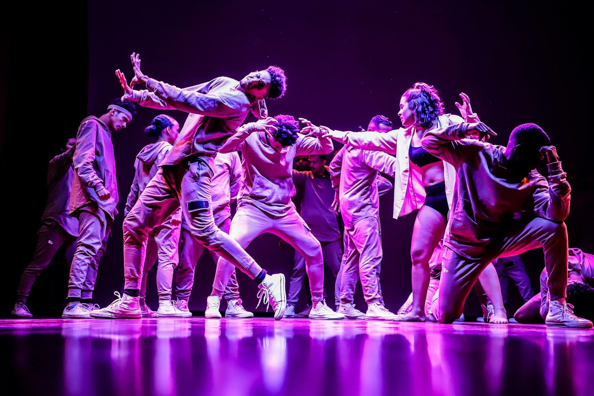 Group of dancers performing on stage under purple lighting