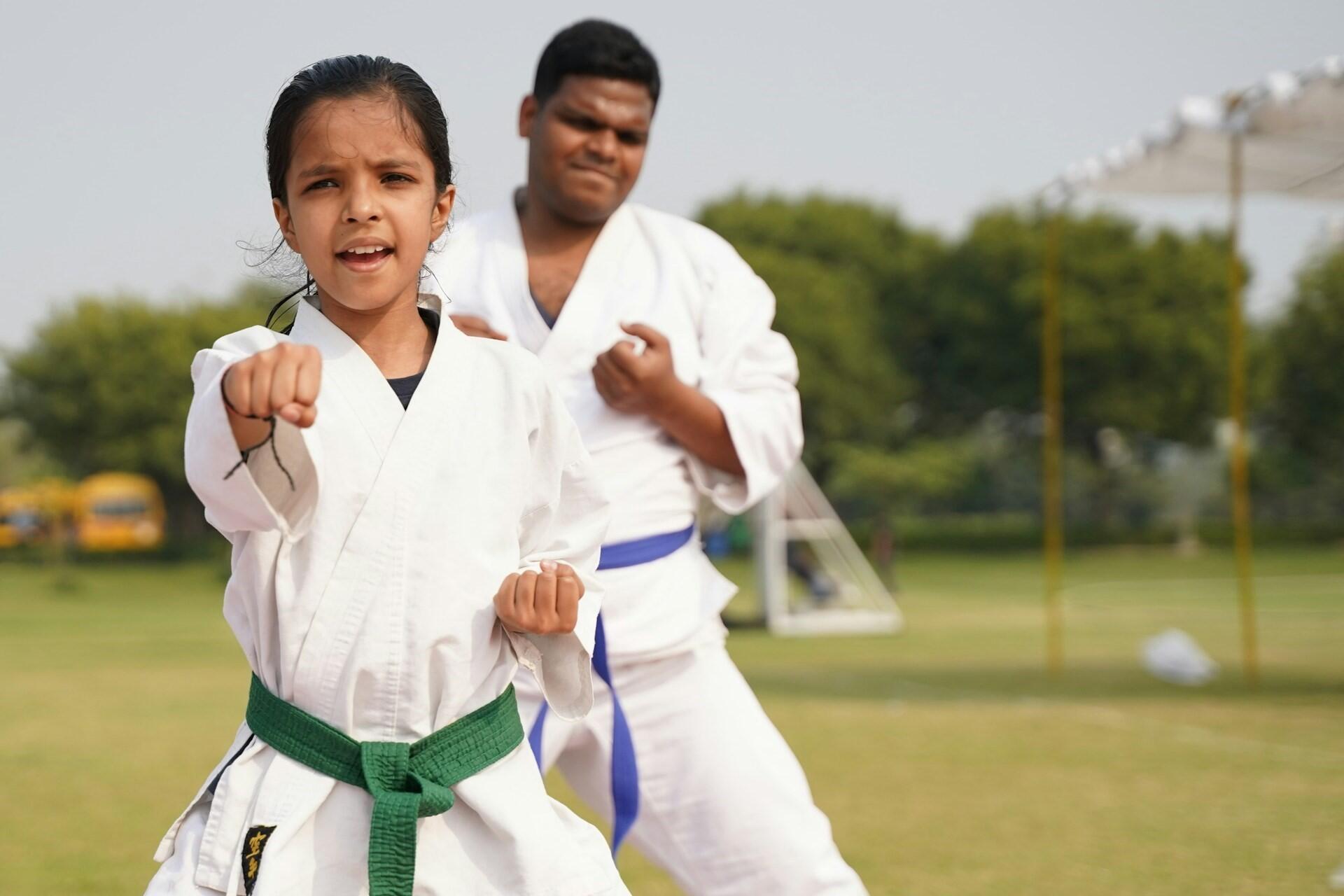 Two kids doing karate outdoors.