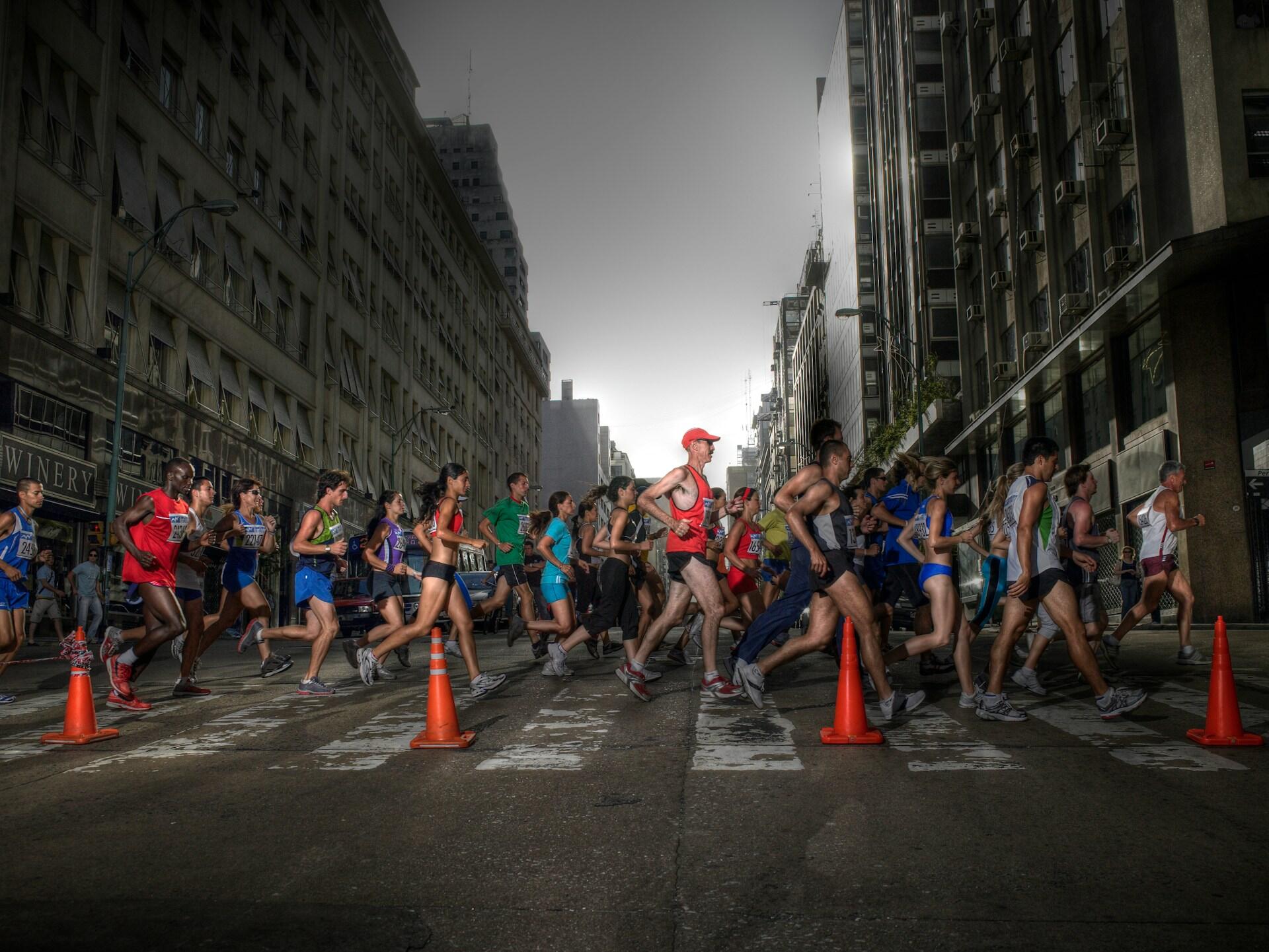 a group of people running a marathon in the evening on a city street