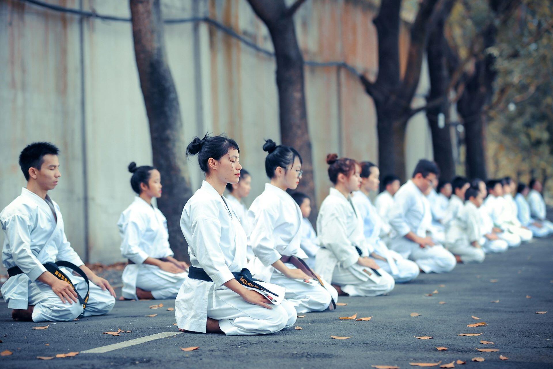 Martial artists kneeling outside.