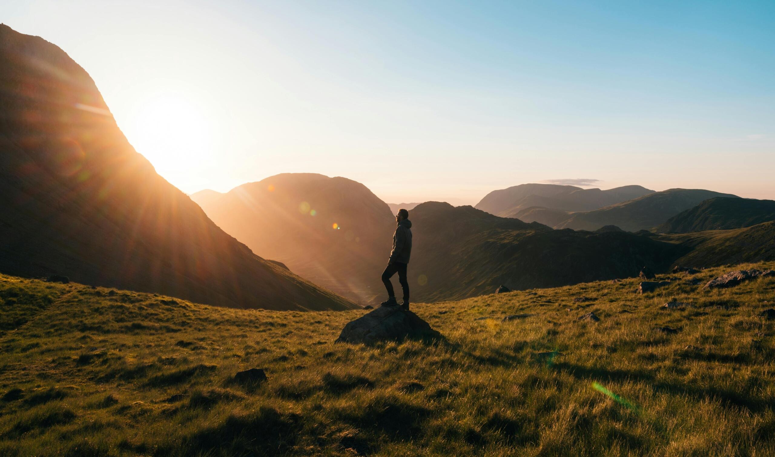 Person standing on mound in mountain glen