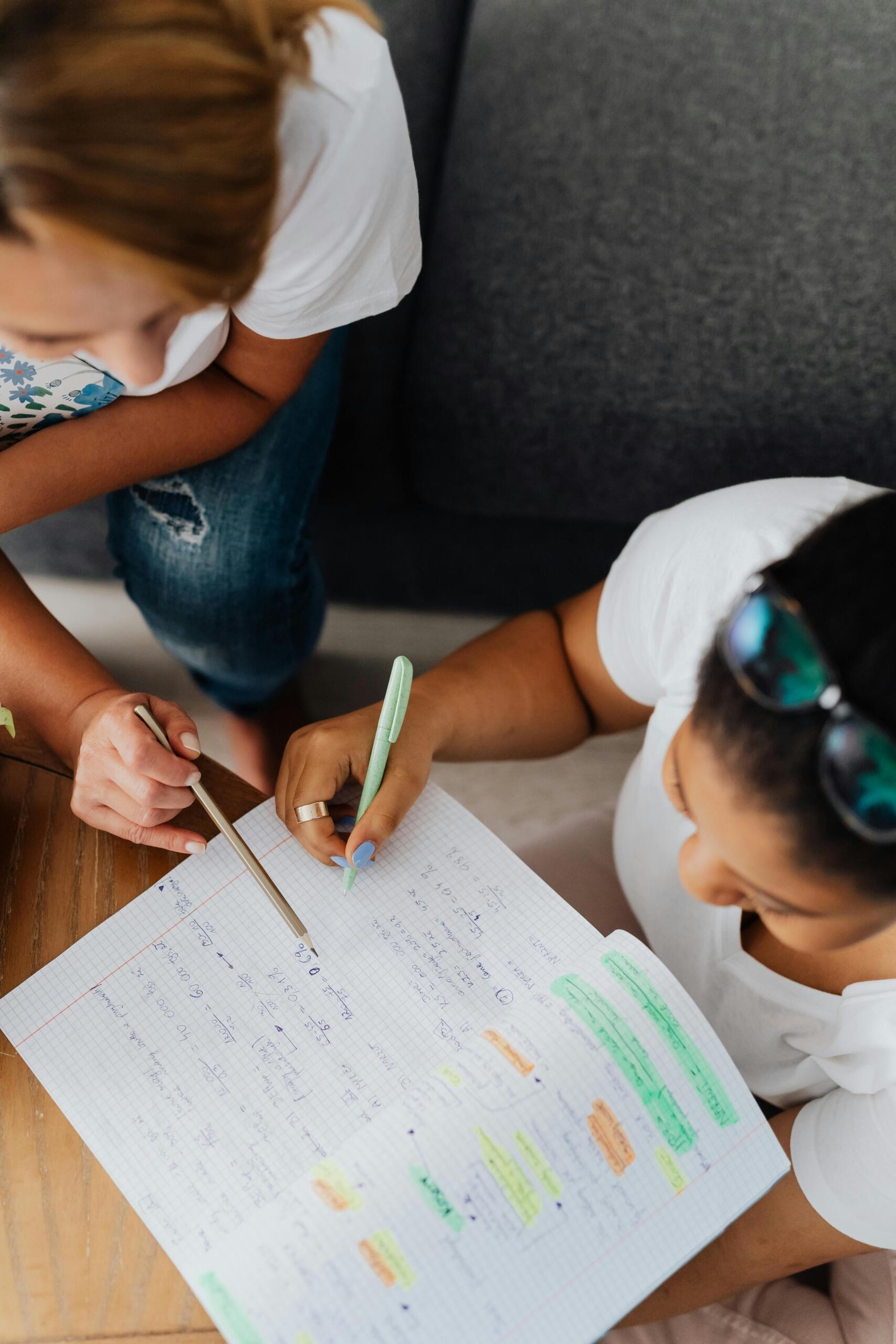 Overhead shot of a teacher tutoring a student at a desk with open notebooks and papers.