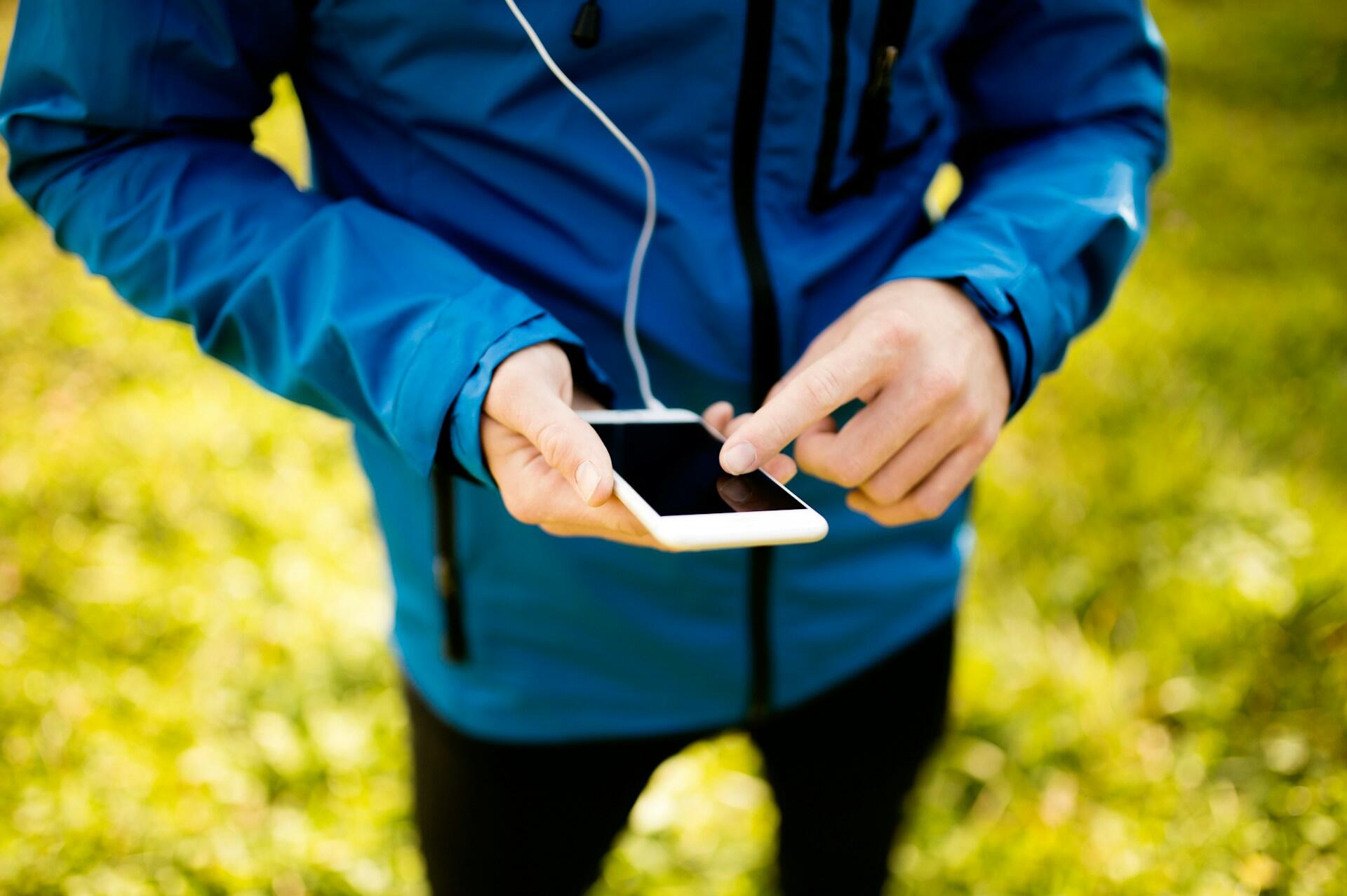 a person in a sports kit looking at their smartphone connected with a headset