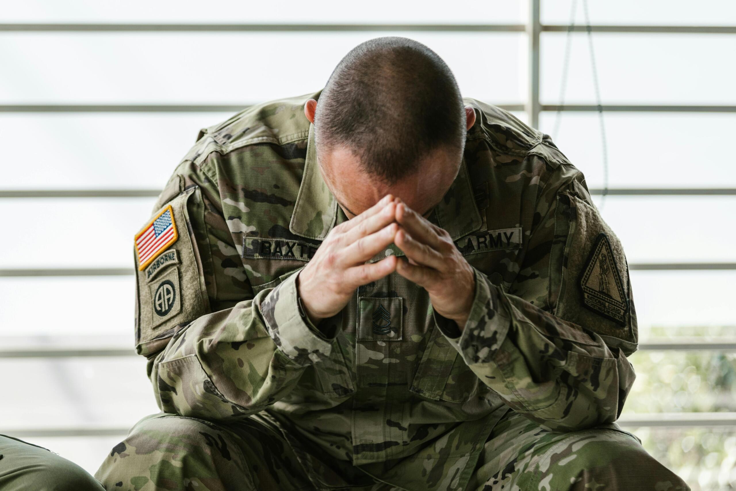 Stressed looking solider holding hands over face