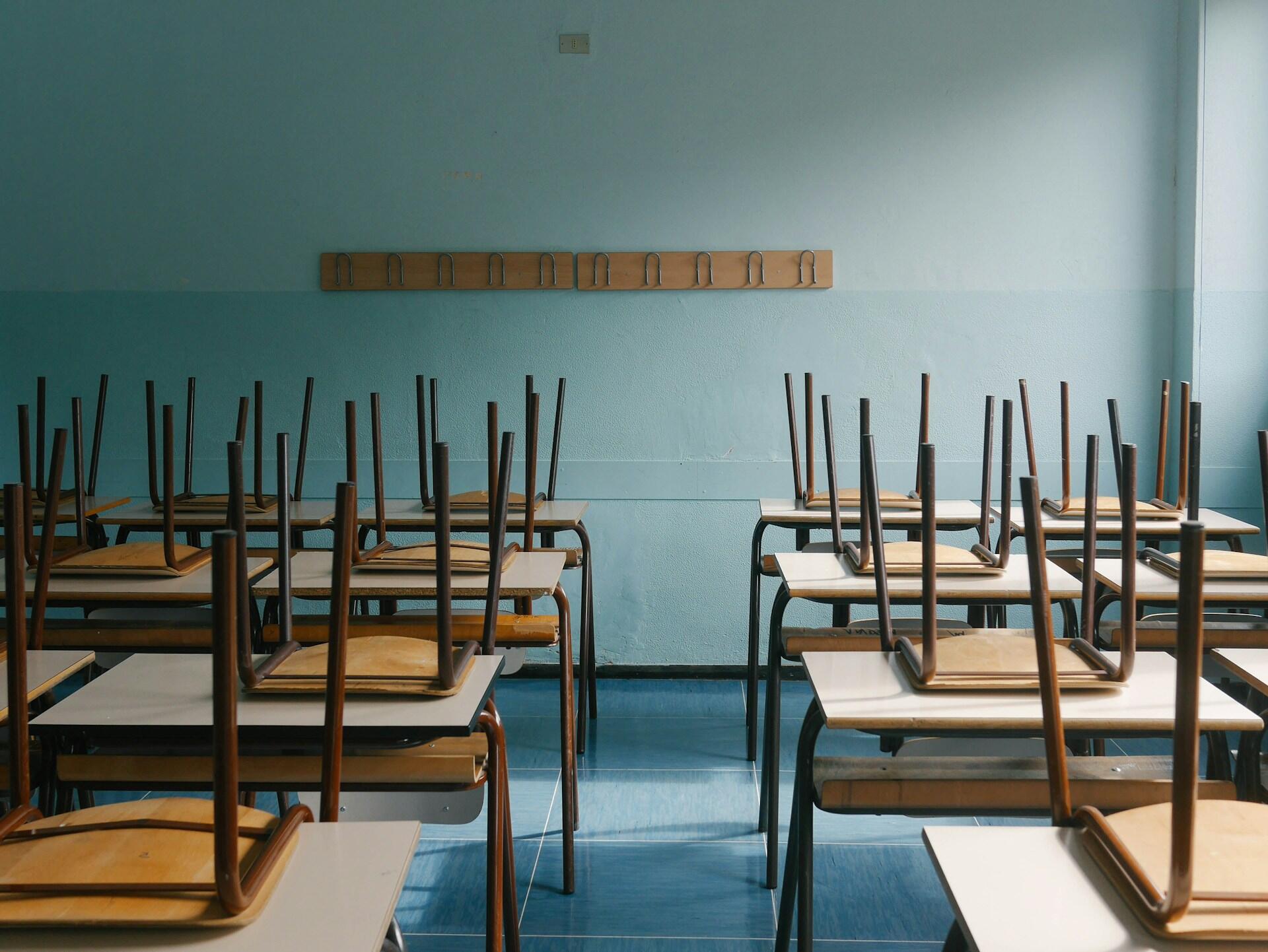 An empty classroom with chairs on desks.