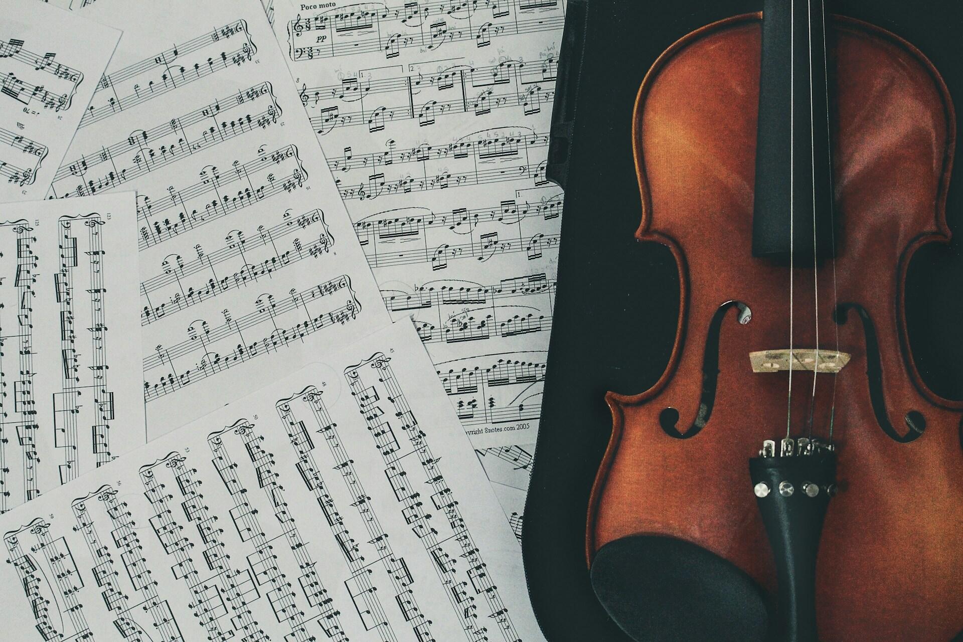 A violin lying next to some sheet music.