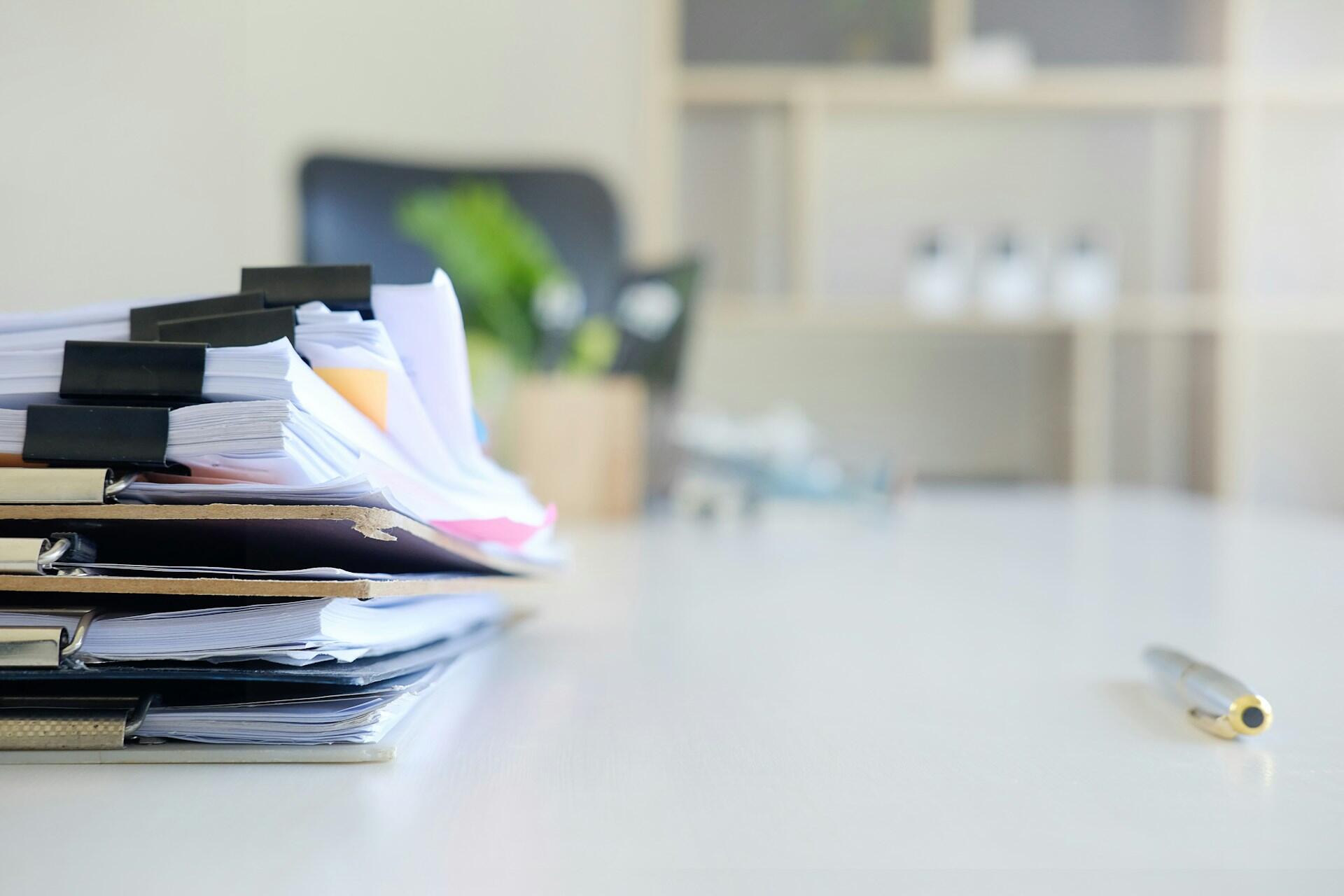 A pile of documents on a white table.