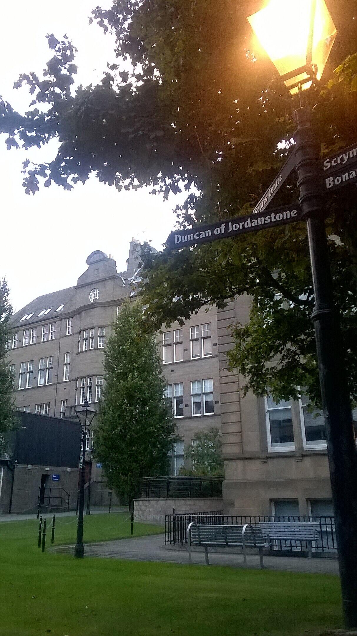 A stone building fronted by a green space at dusk.