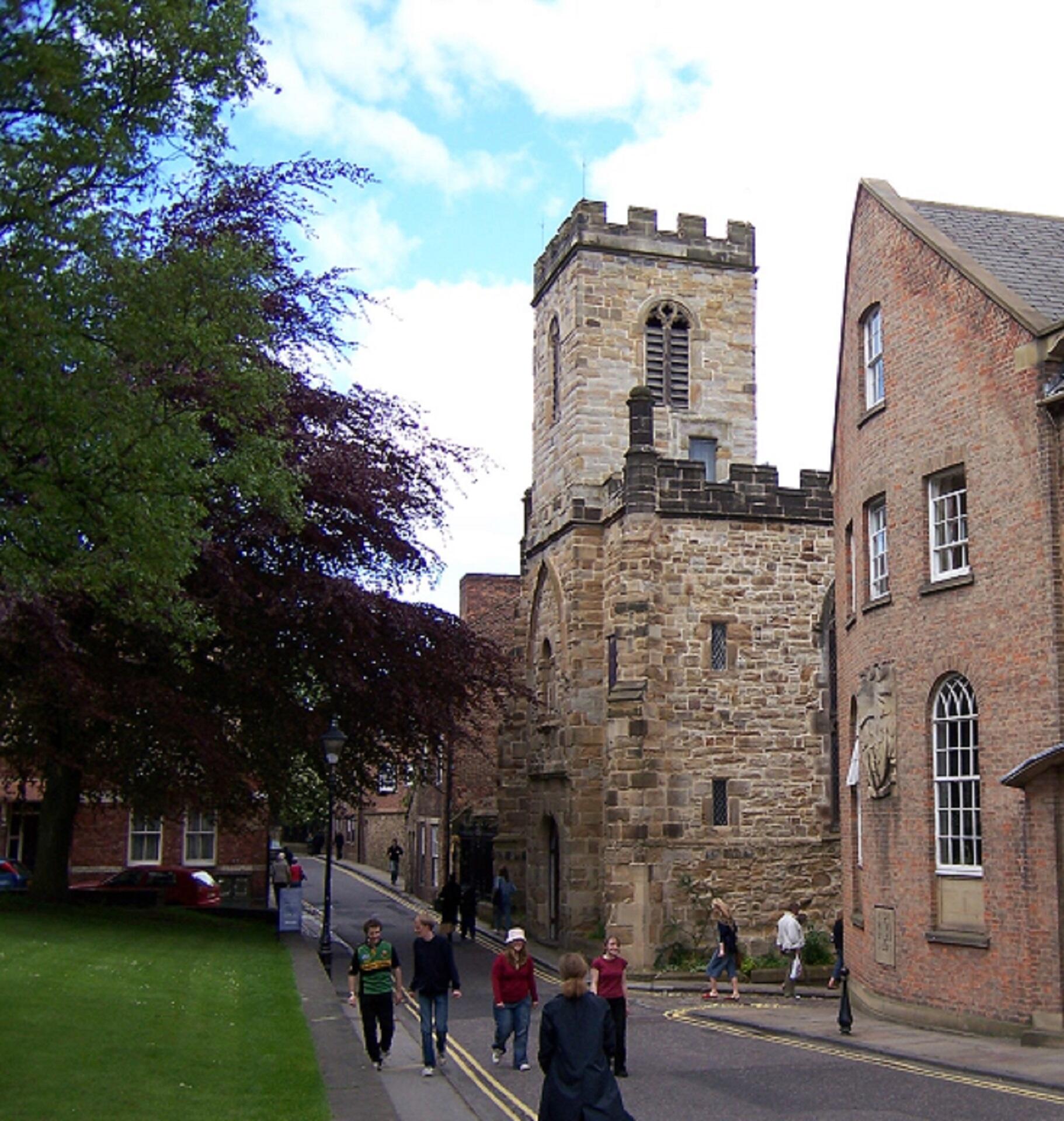 People walking in front of a large stone building.