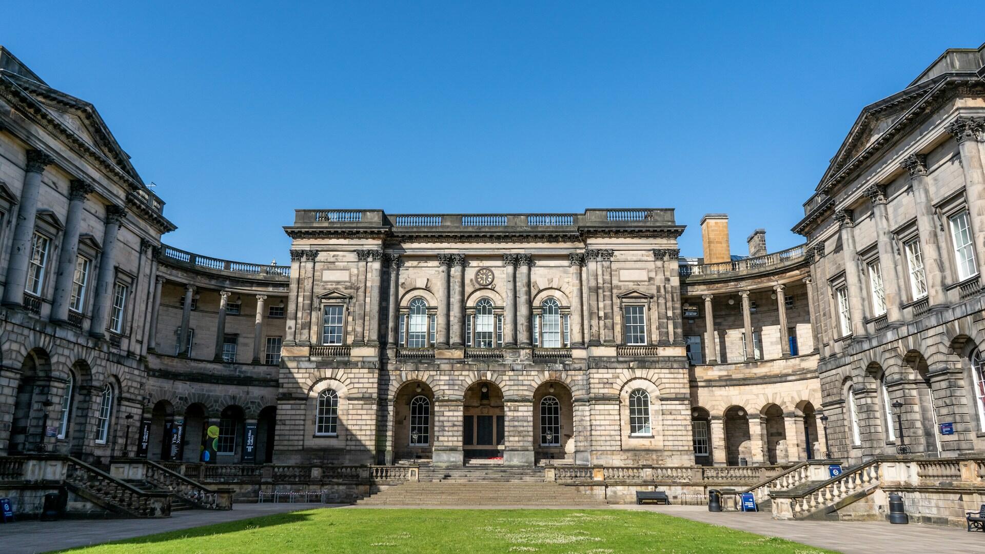 A large building with a green lawn on a sunny day. 