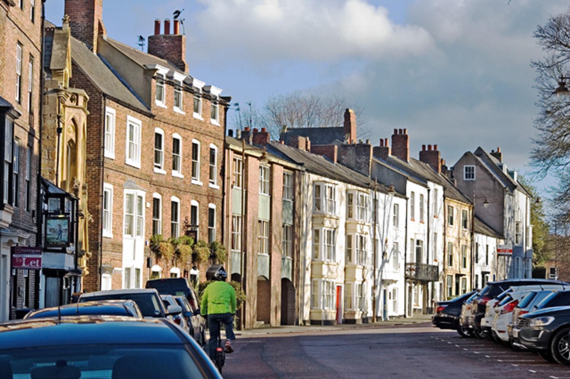 A cyclist rides past a row of buildings.
