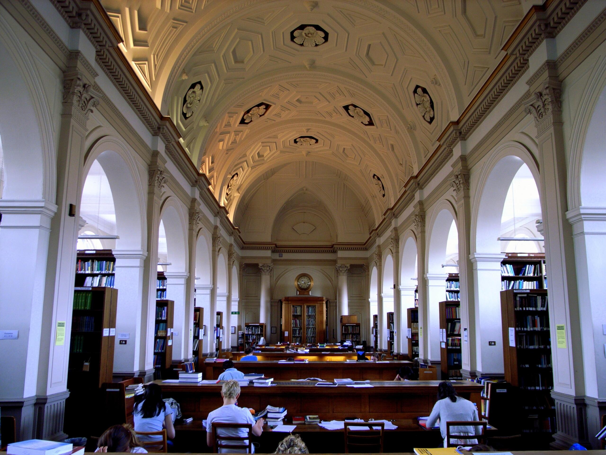 A room with a vaulted ceiling and people sitting at tables. 