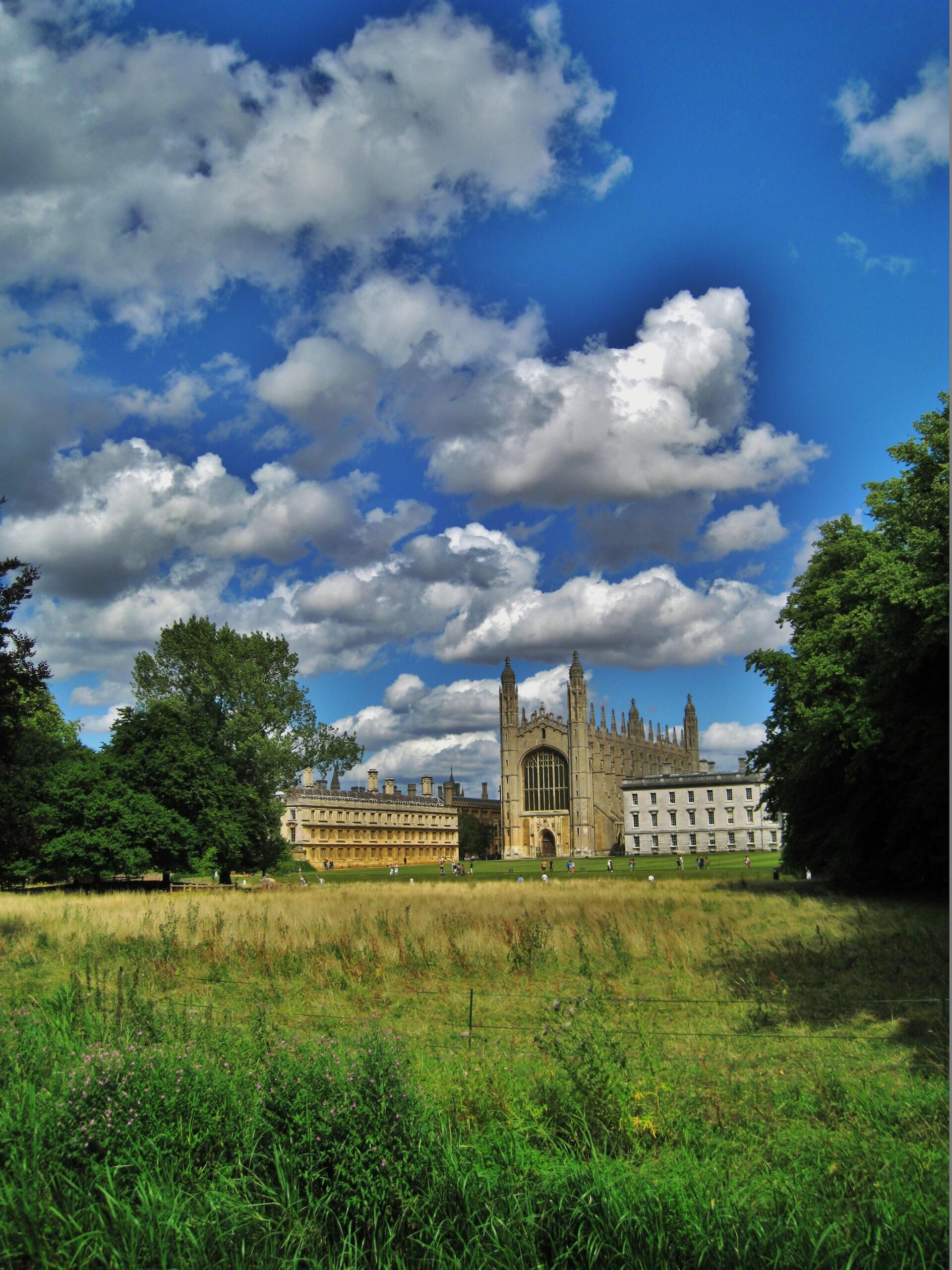 An open green space with a stone building in the background. 