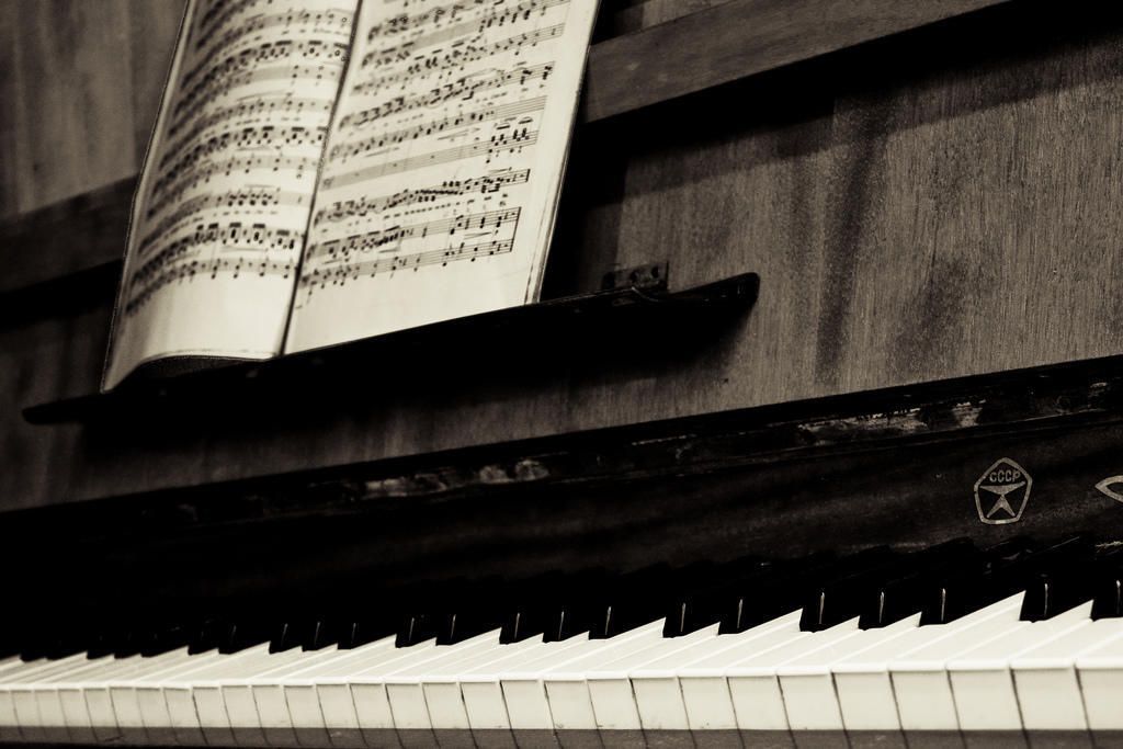 a black and white image of a piano with sheet music