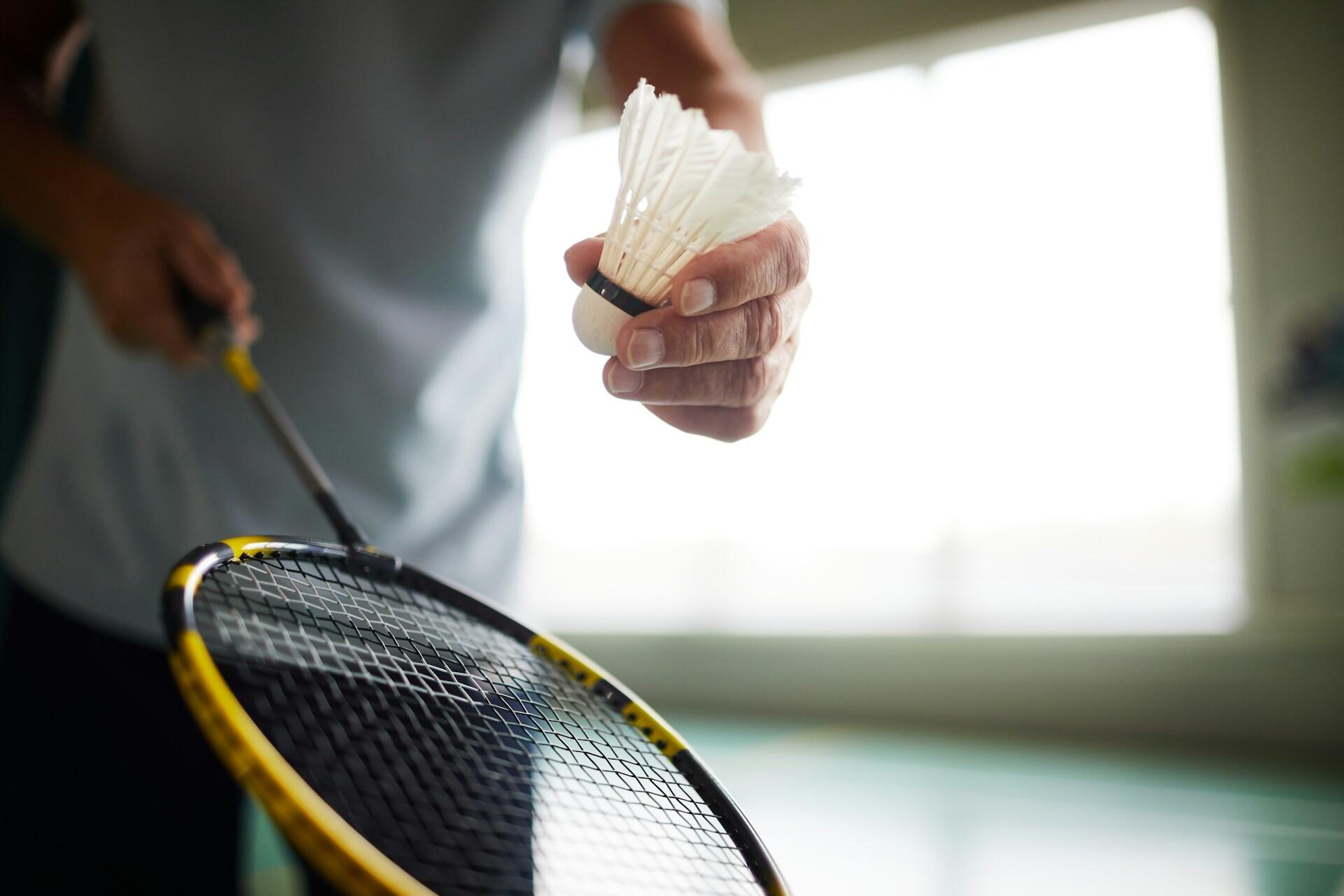 A person holding a badminton birdie and racket.