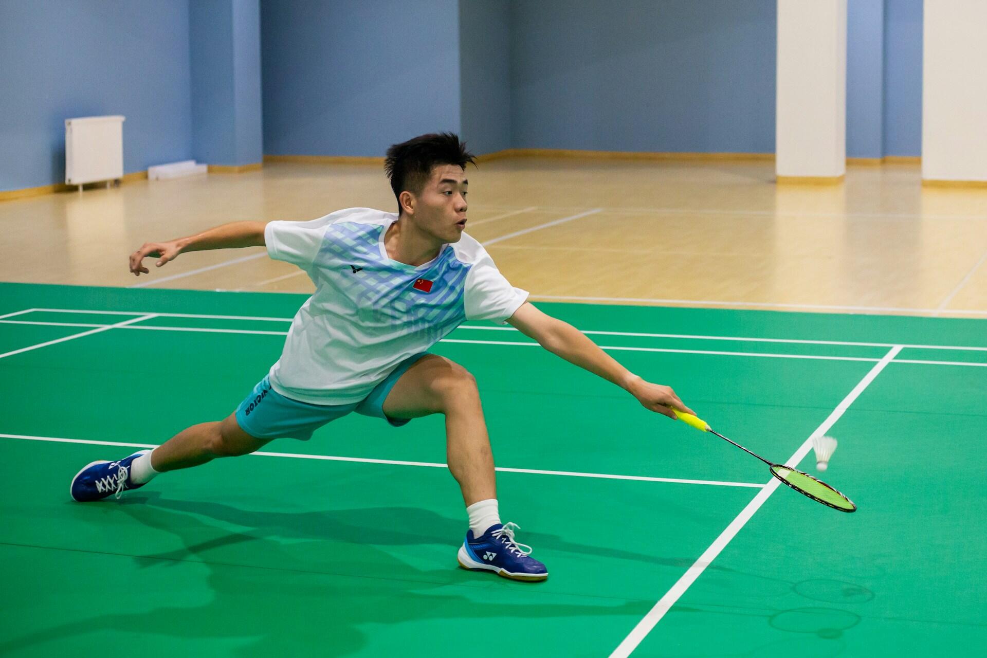 A man playing badminton on an indoor court. 