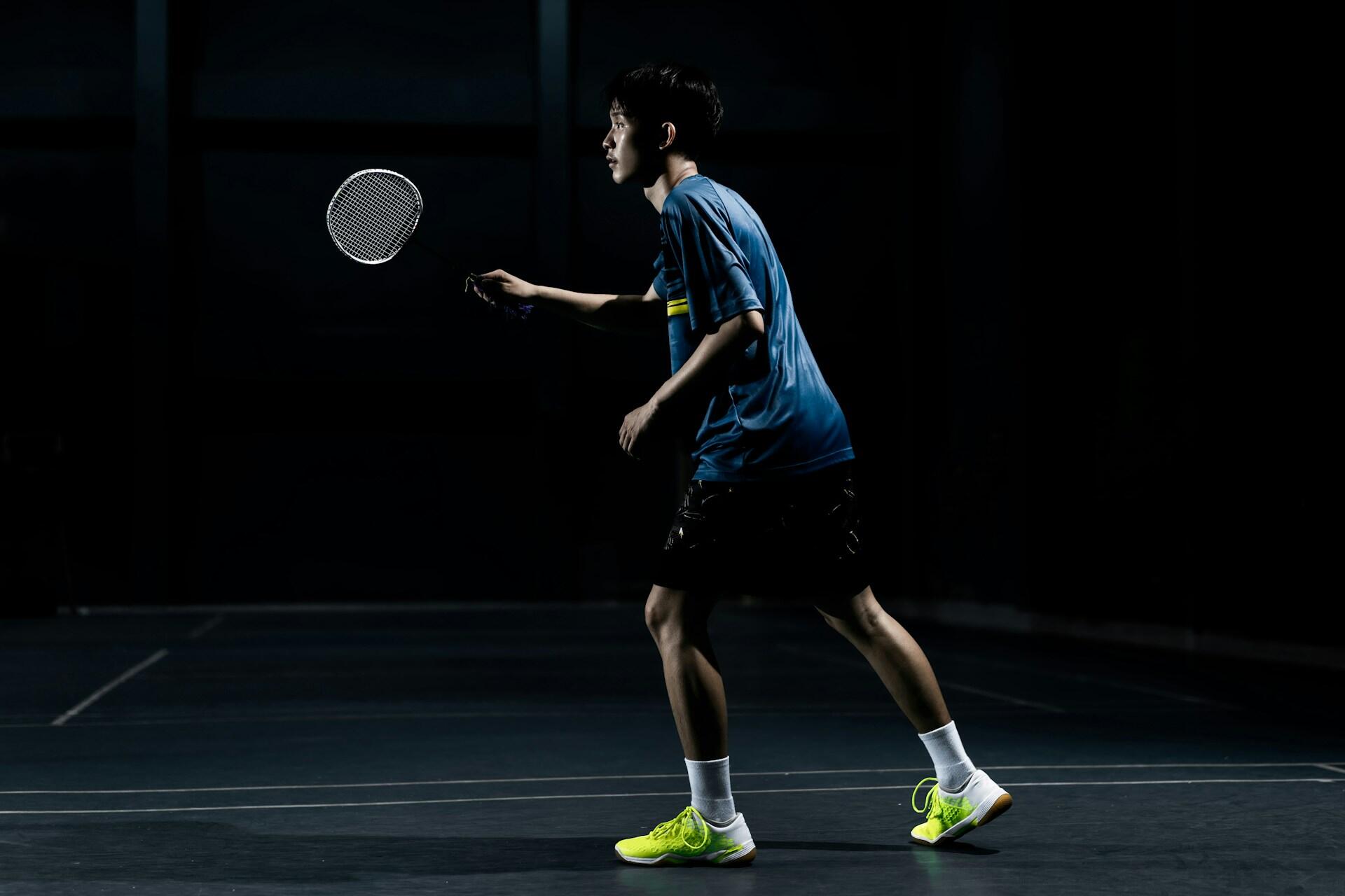 A badminton player holding their racket aloft.
