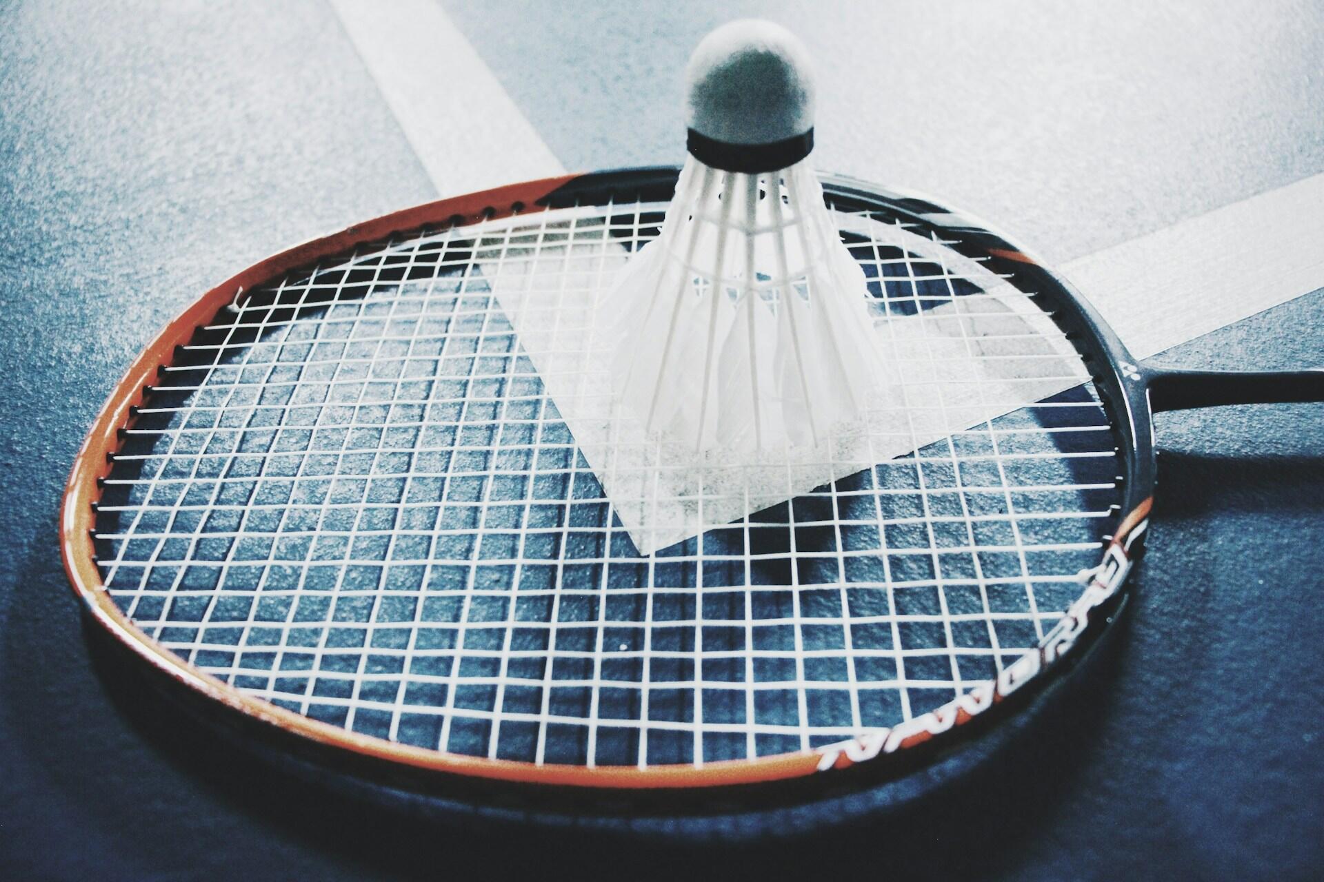 A badminton racket and shuttlecock laying on the badminton court.