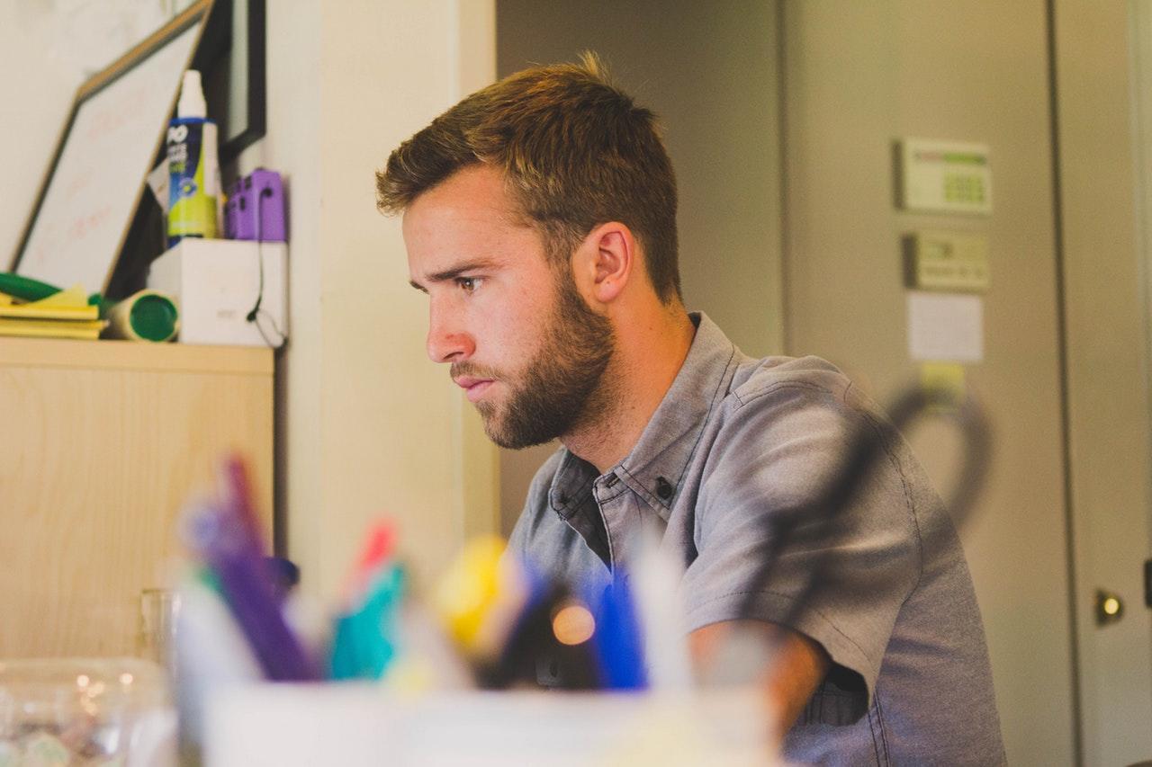 man working at a desk with a close-up of desk materials and stationery