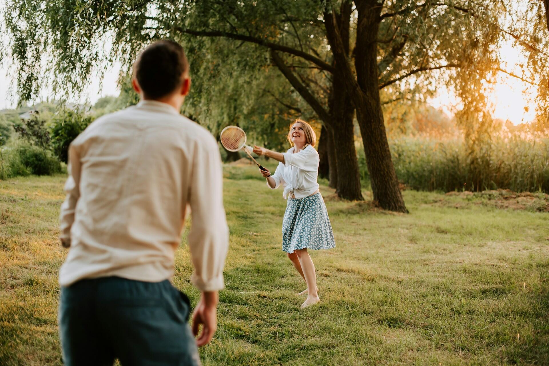 Two people playing badminton at sunset. 