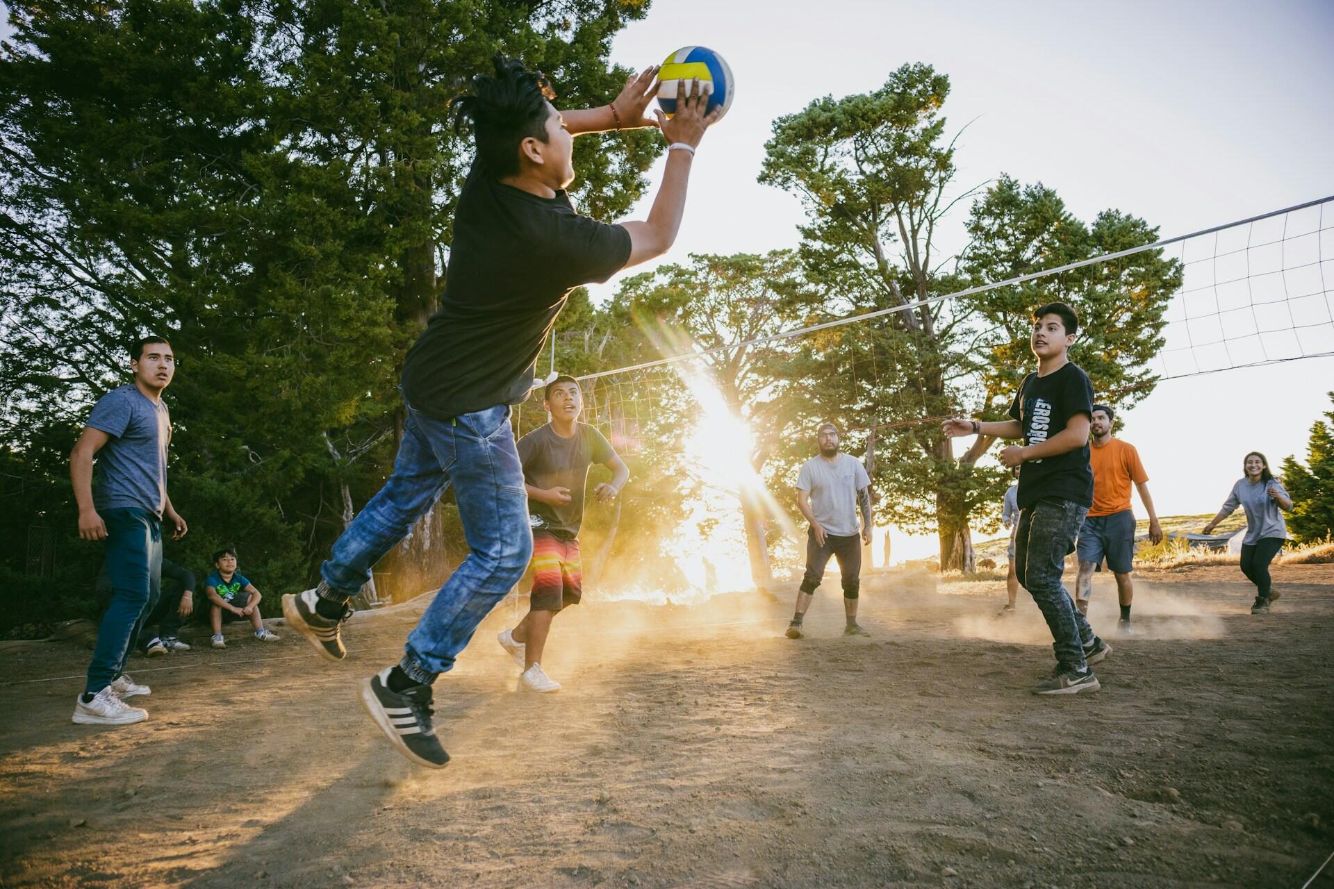 A group of people playing a casual game of volleyball.
