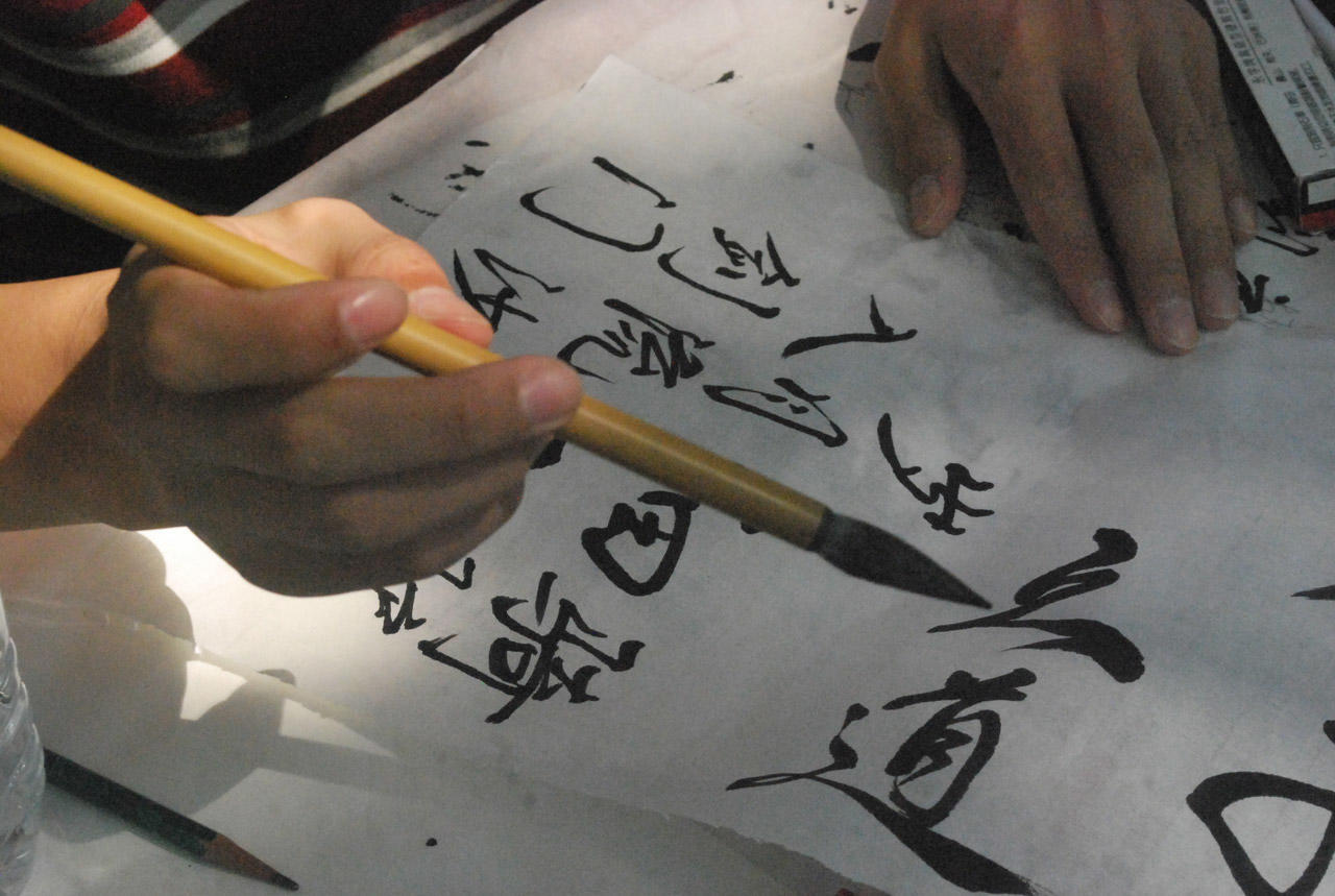 person writing chinese calligraphy with a brush