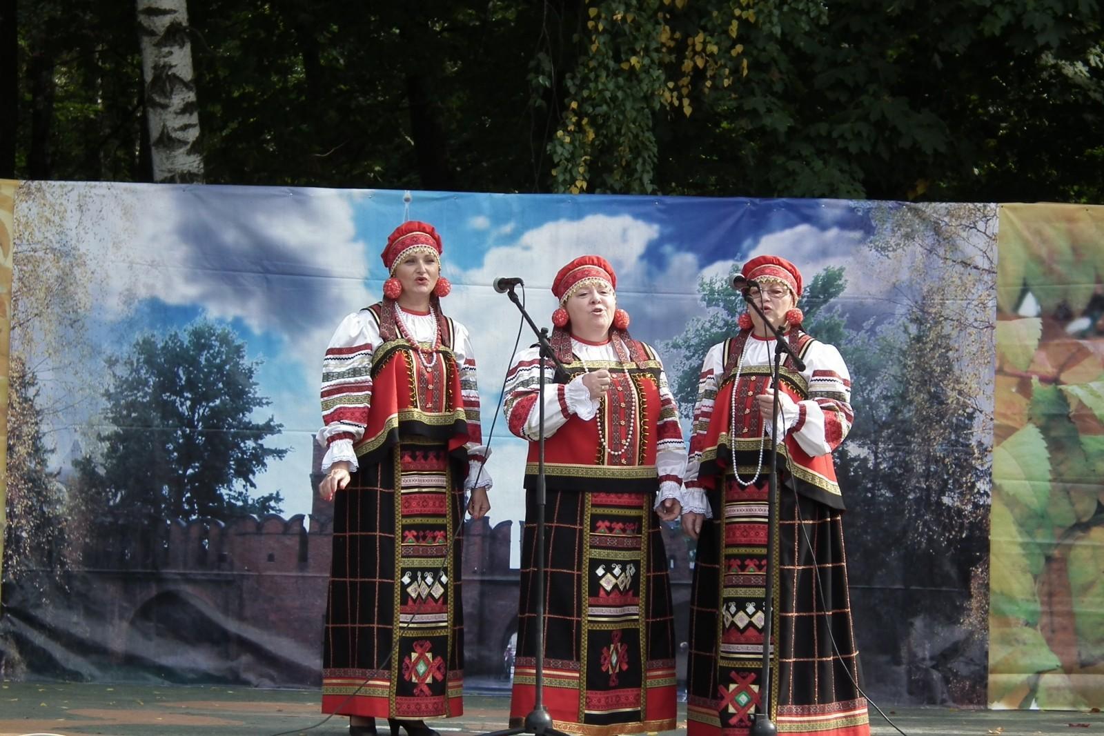 three woman dressed in traditional clothing standing in front of microphones on a stage