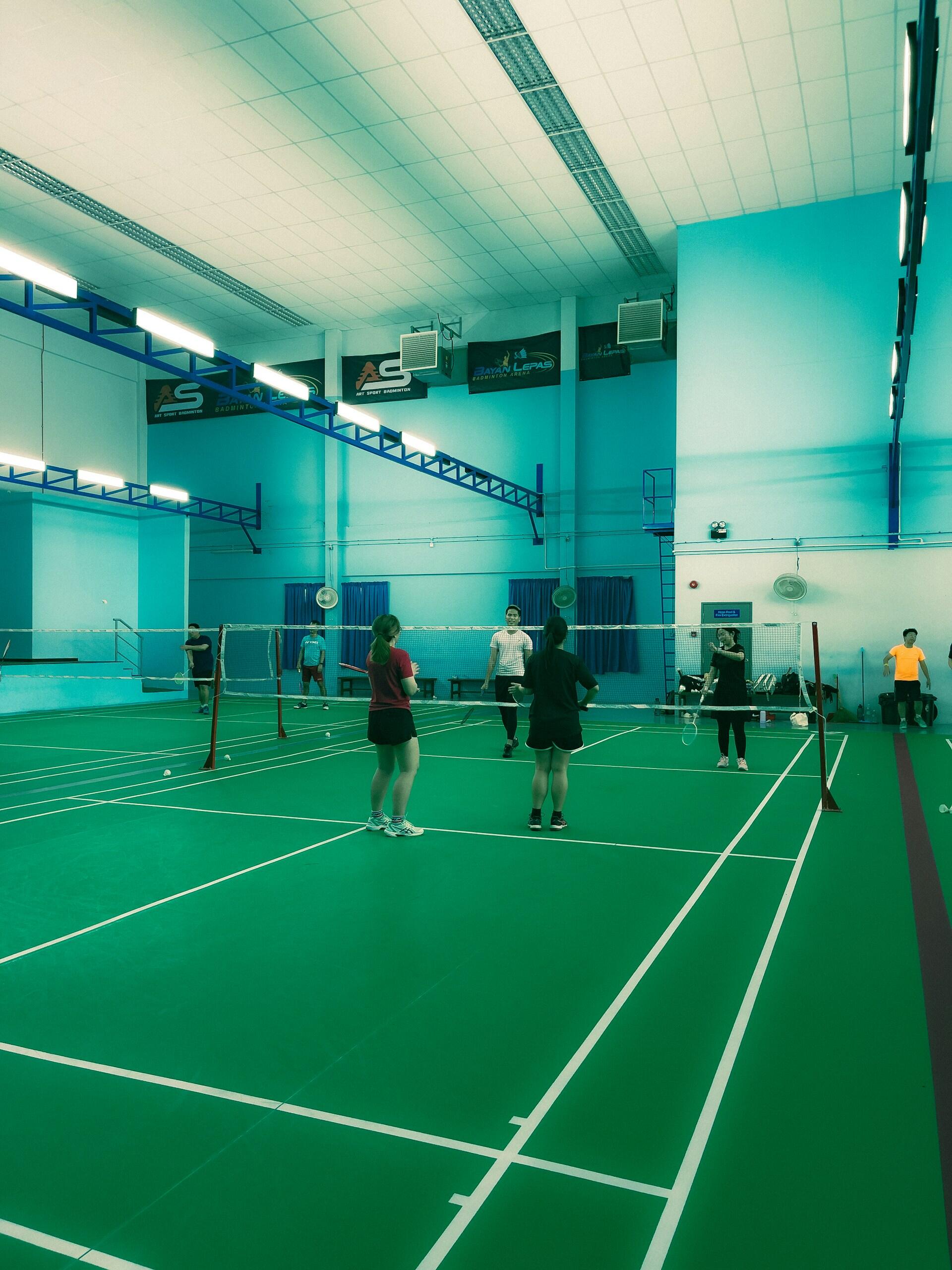 People standing on an indoor badminton court.