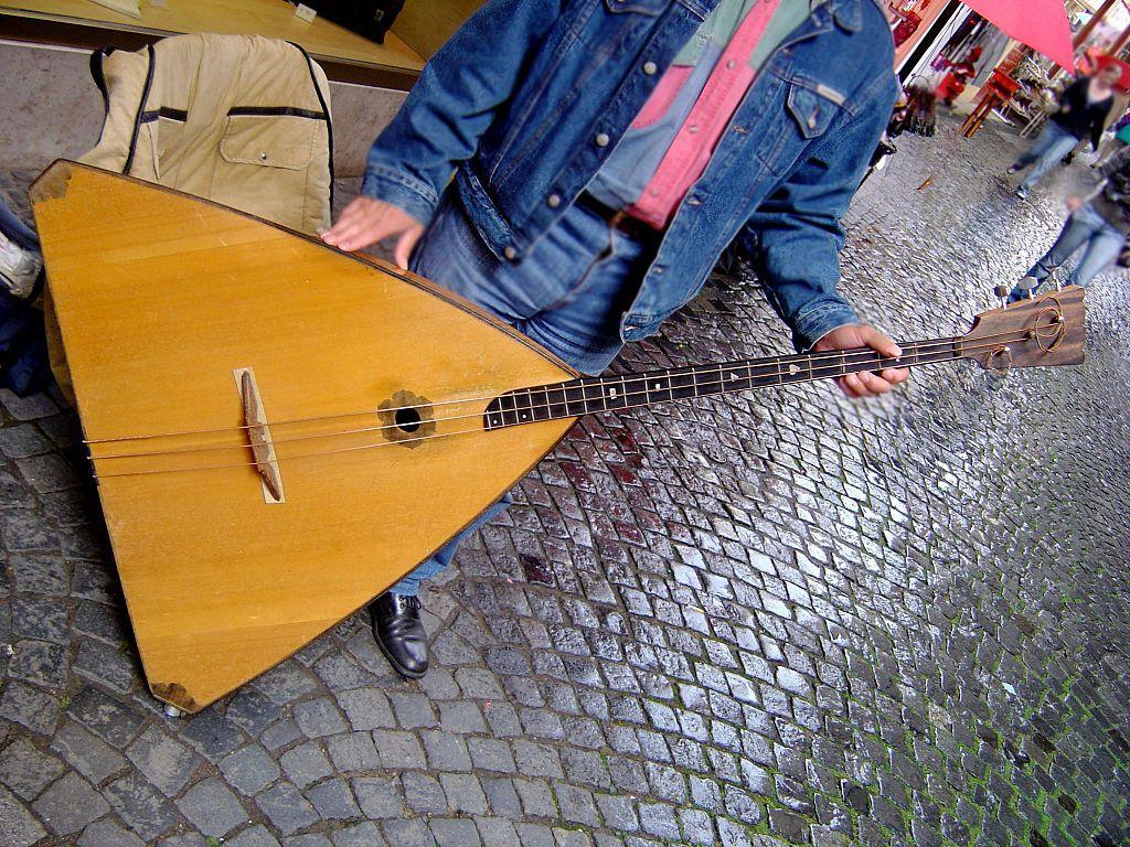 a person holding a triangular lute standing in a street