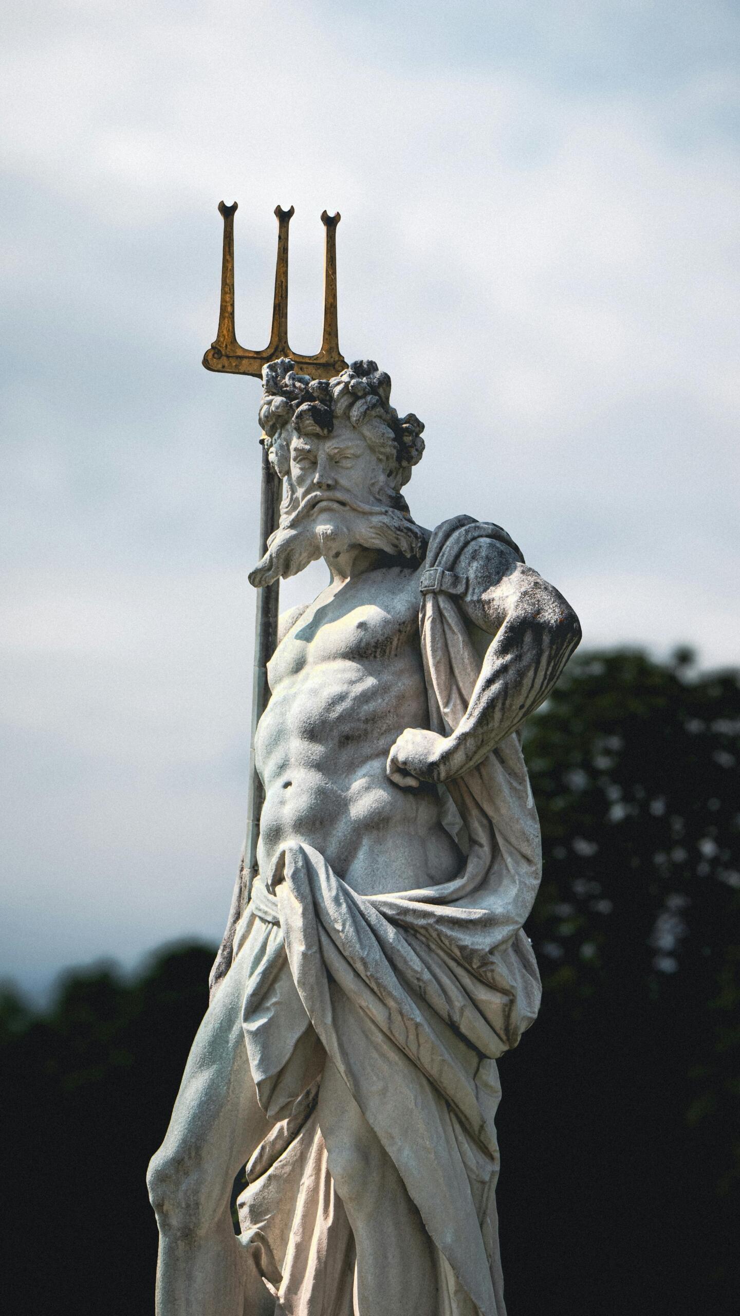 Statue of Poseidon holding a trident, depicted with flowing beard and muscular form, symbolizing the Greek god of the sea.