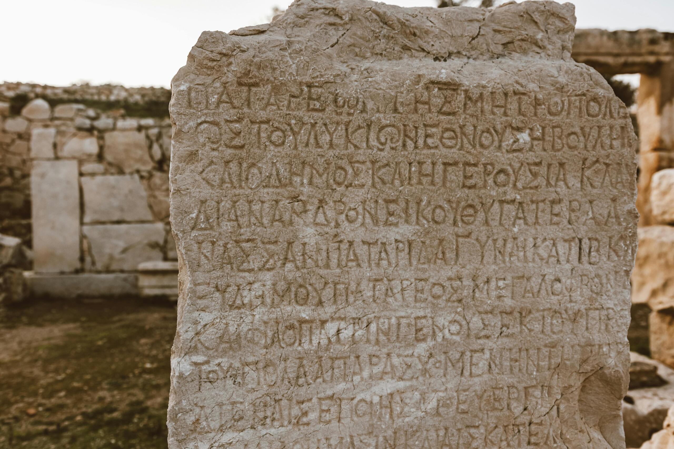 Ancient stone tablet engraved with Greek writing, featuring weathered and carved letters in classical script.