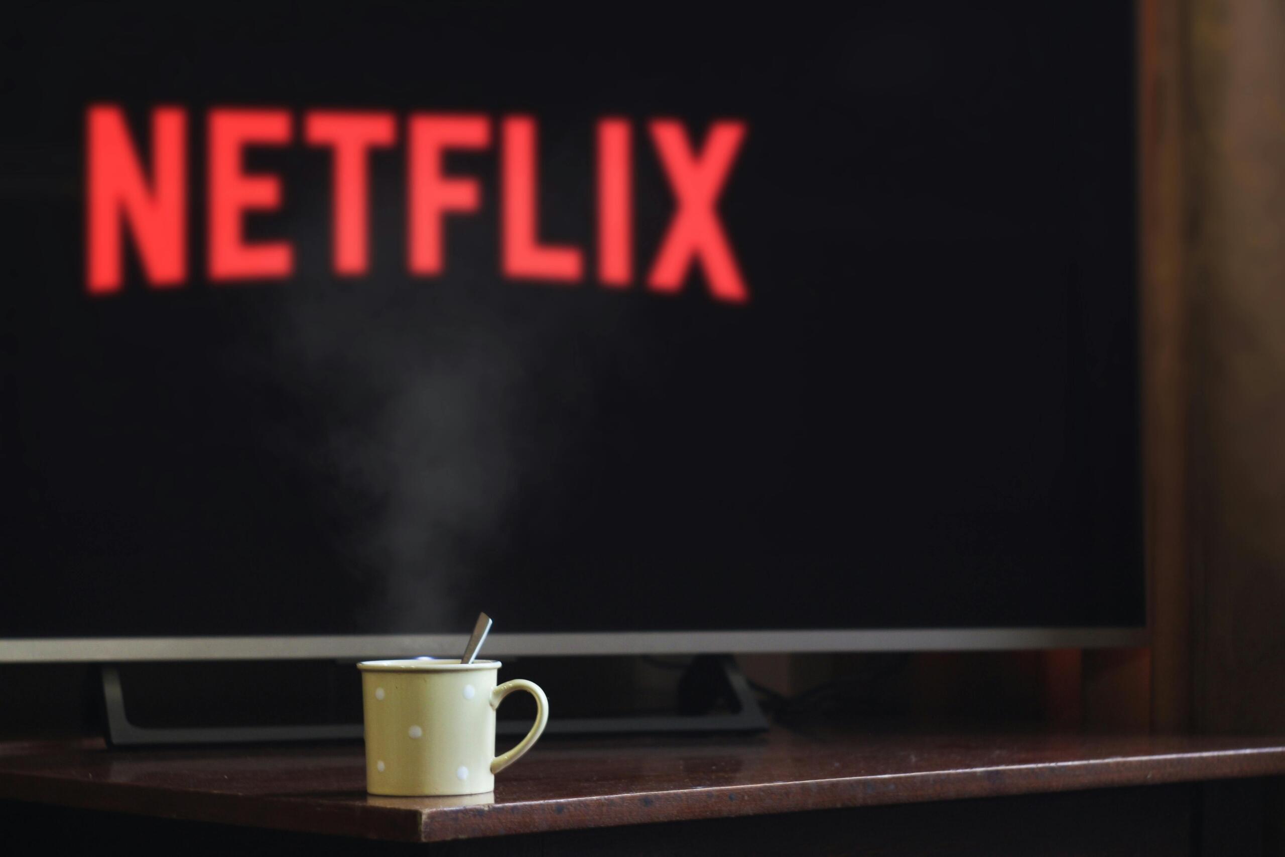 Mug placed on a table in front of a screen displaying the Netflix logo.