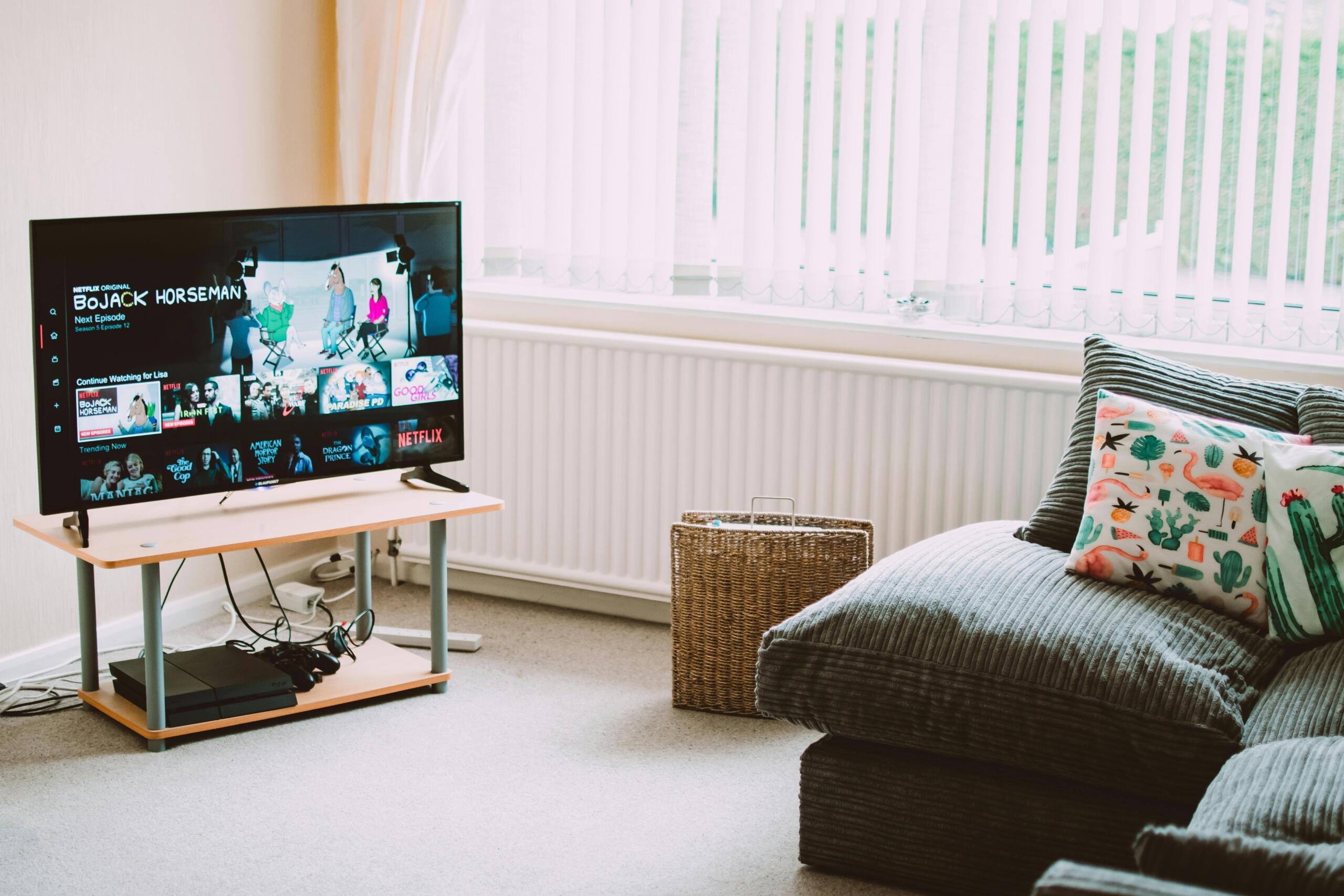 Cozy living room with a television turned on, showing a bright screen, surrounded by a couch, coffee table, and soft lighting.