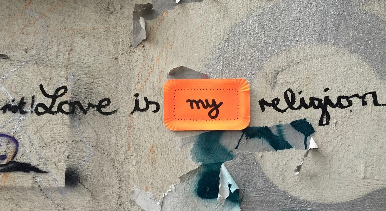 The words 'love is my religion' written in grafitti in a wall
