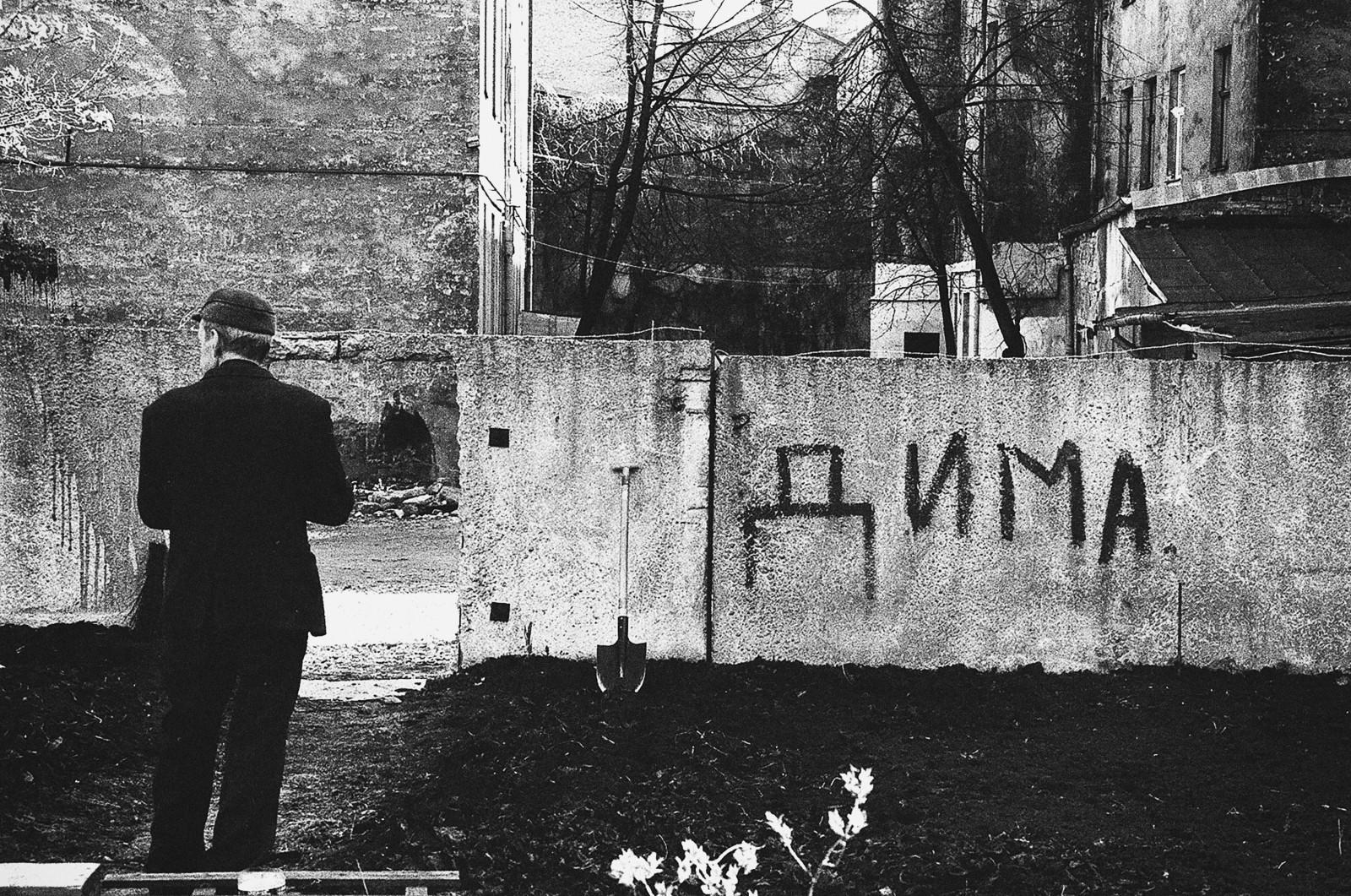 a man standing in front of an old building with grafitti written on it