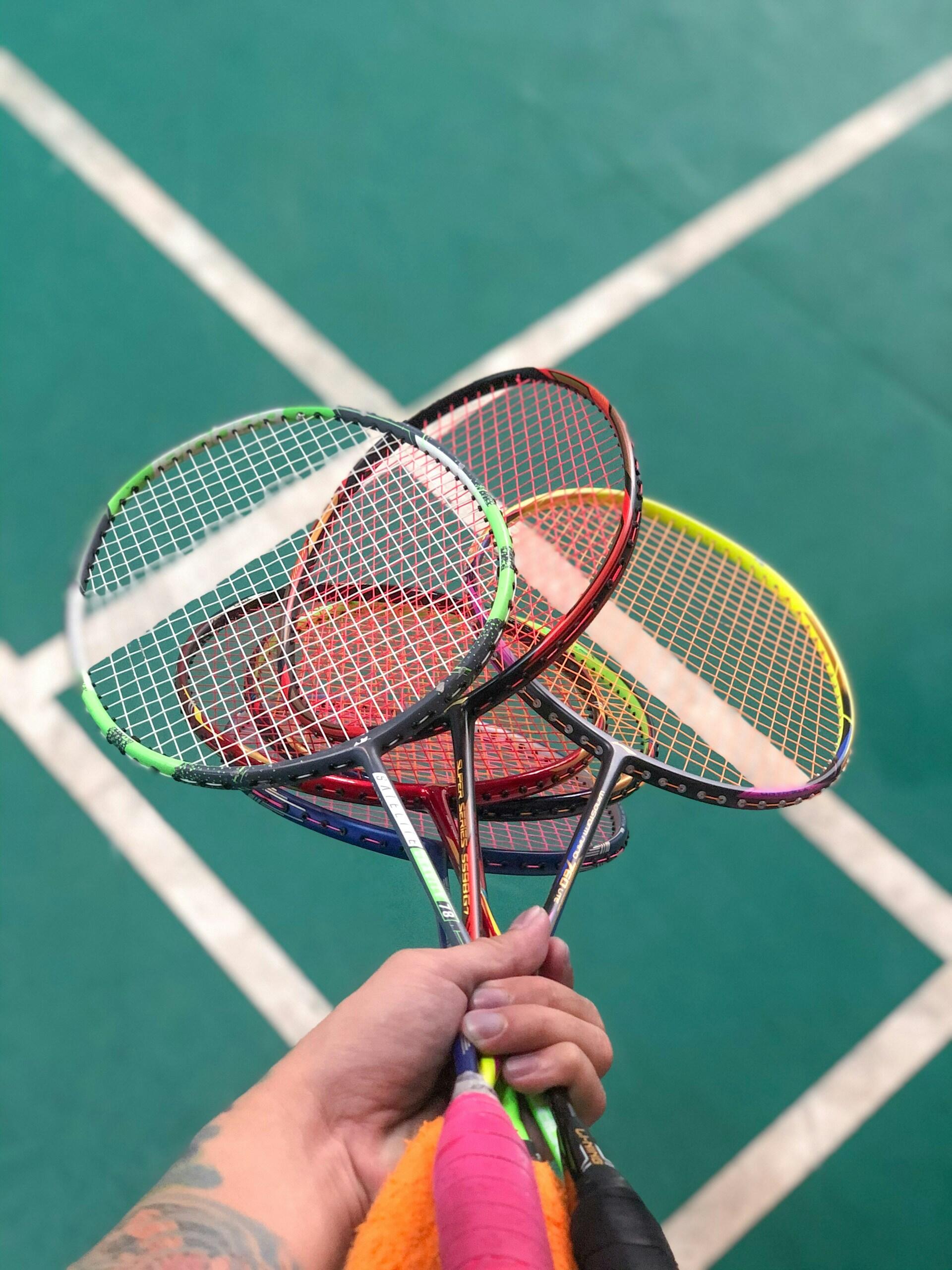 A person holding a bundle of badminton rackets. 