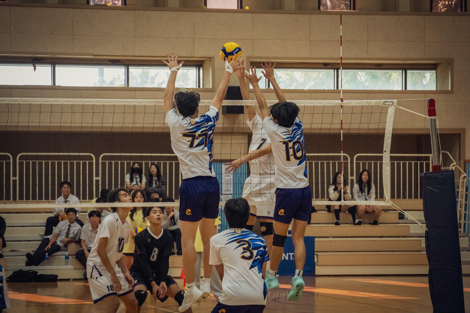 An opposite hitter and middle blocker blocking a volleyball shot.