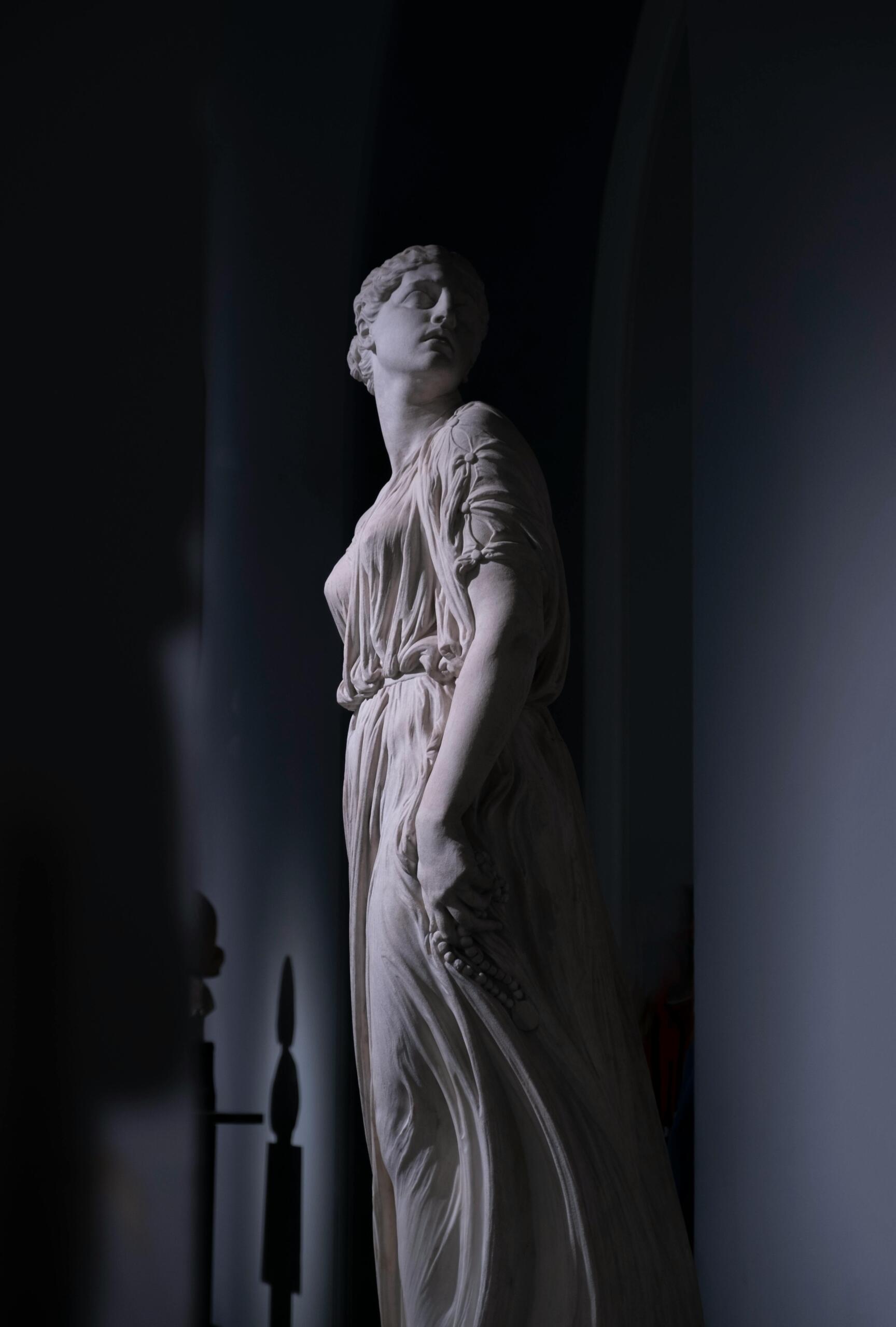 Marble sculpture of a Greek goddess in flowing robes, showcasing classical features and graceful posture.