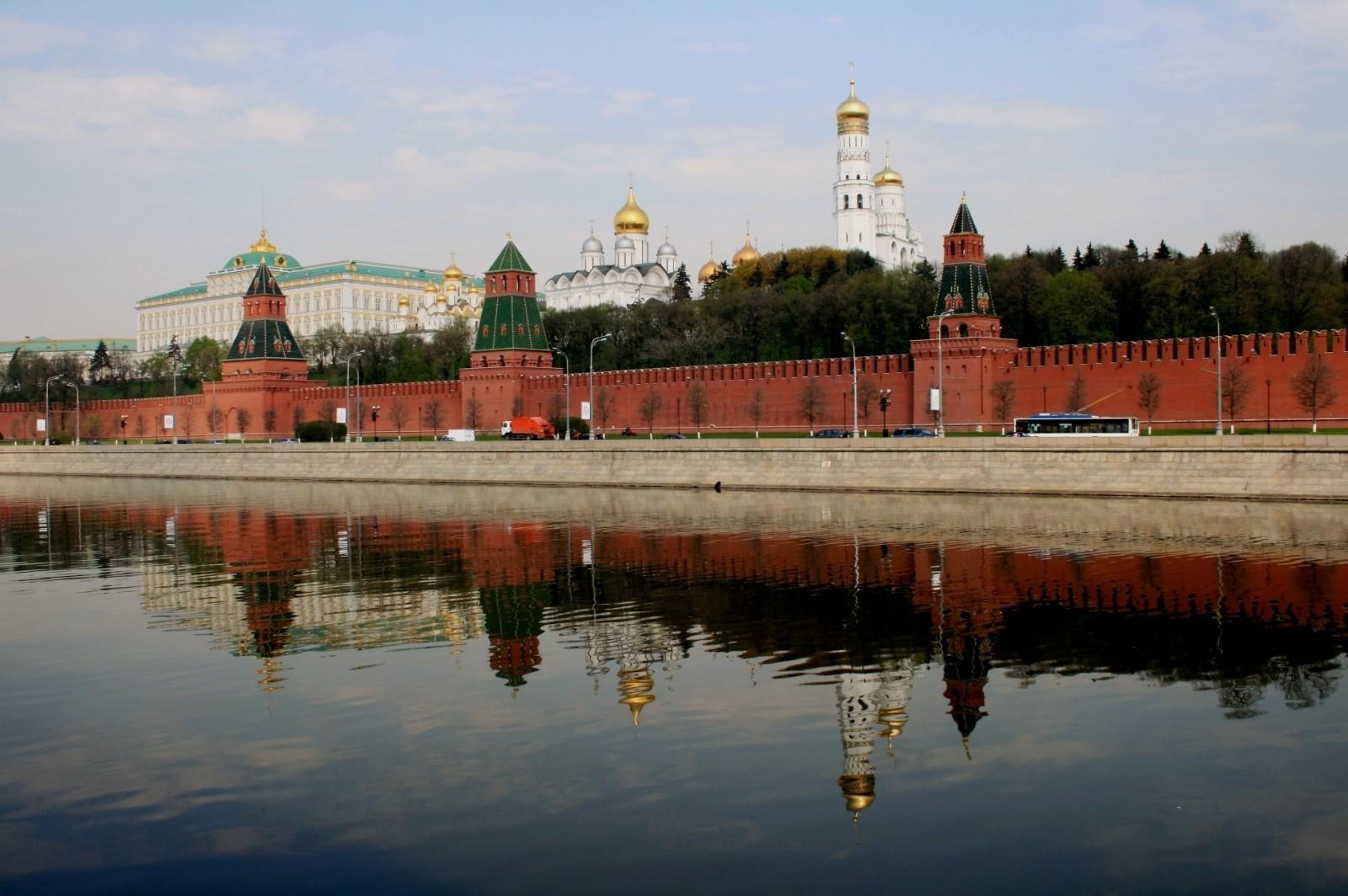 an old building surrounded by a red fence along the edge of a river 