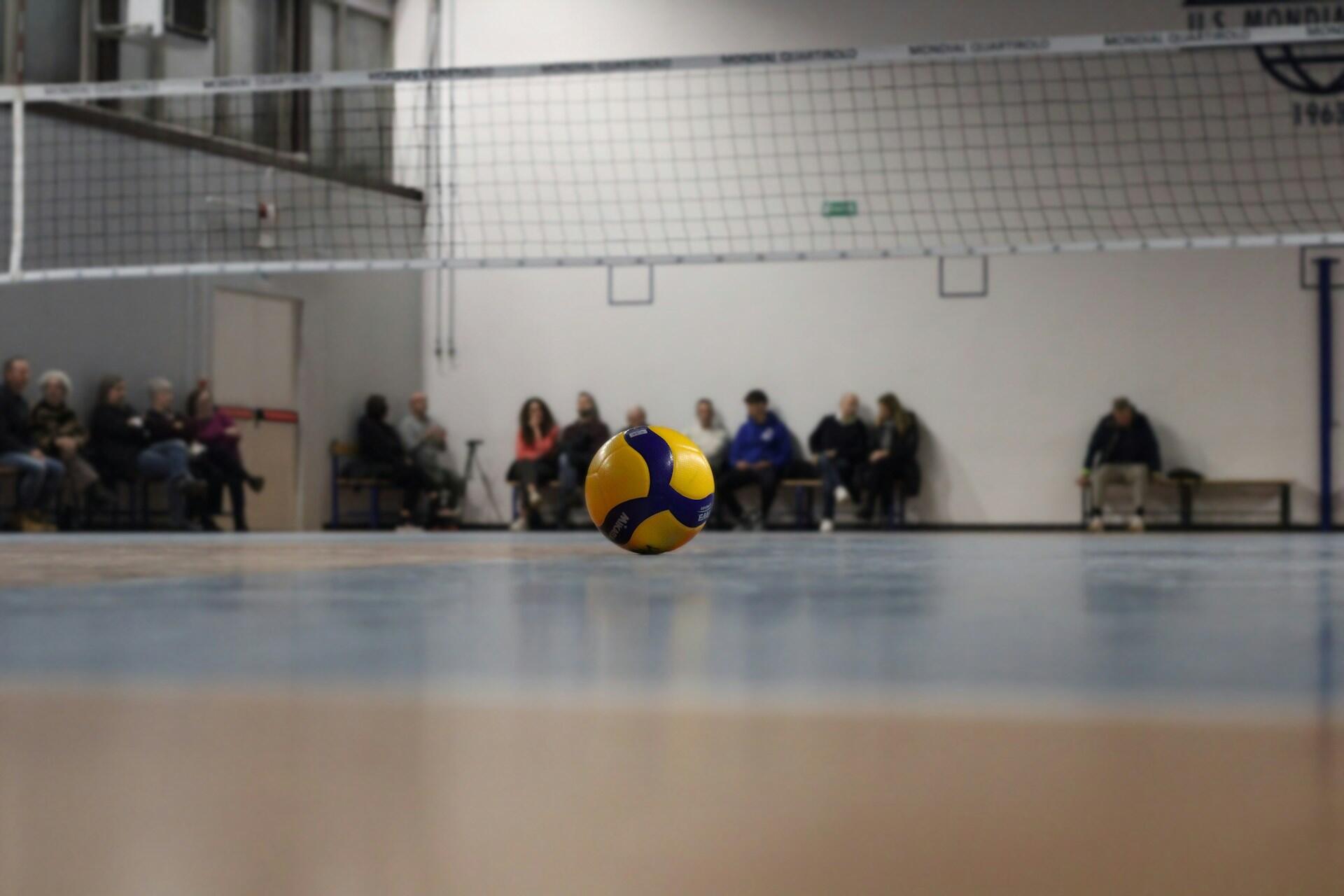 A volleyball lying on a volleyball court.