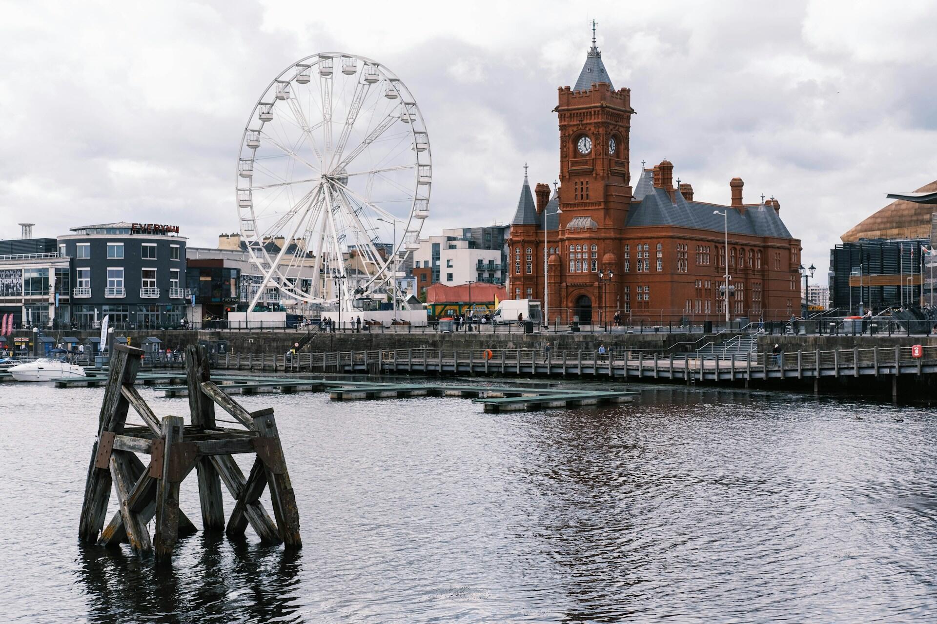 A giant wheel in front of a red brick building.