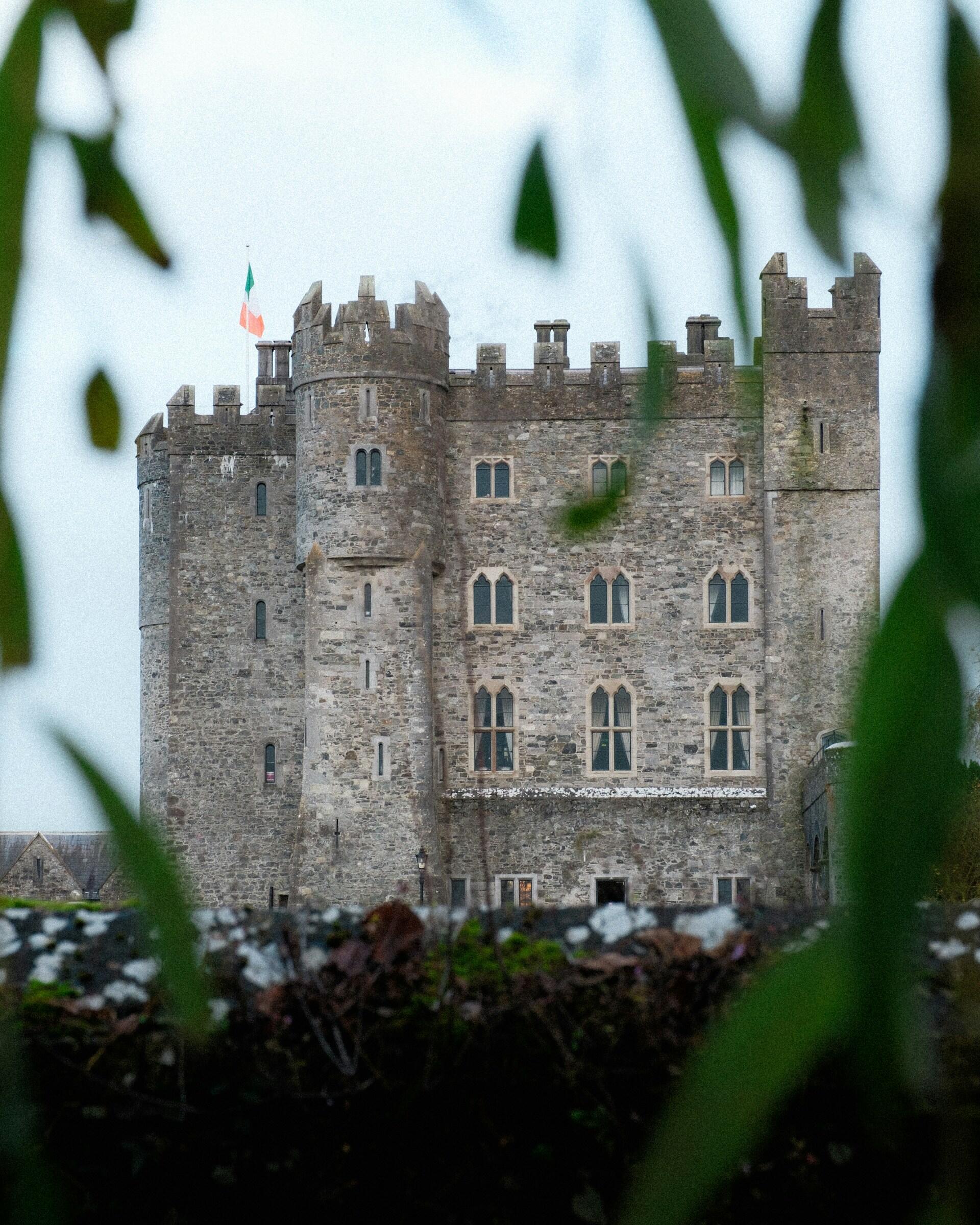 A large stone castle with an Irish flag atop.