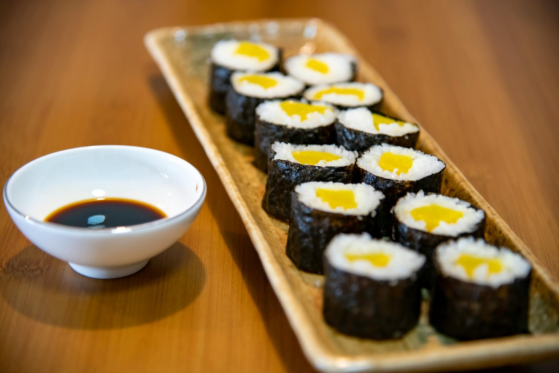 a plate of sushi with a bowl of soy sauce