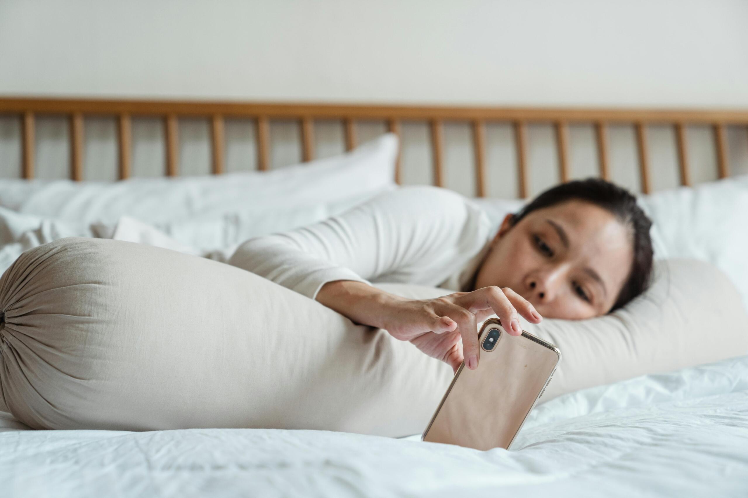 woman lying in bed looking at a smartphone