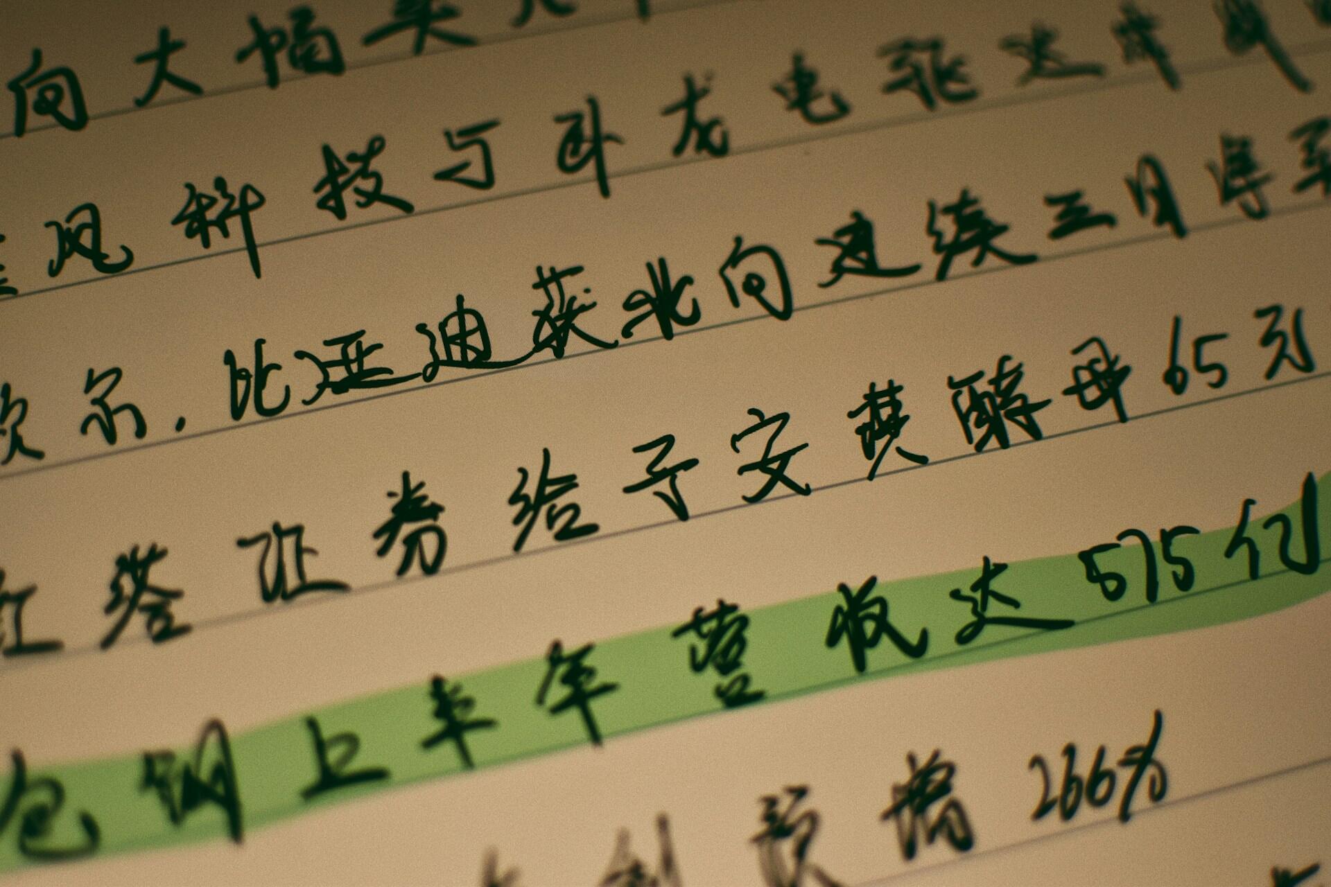 Close-up of handwritten Chinese text with green highlighting, featuring notes or a message on lined paper.